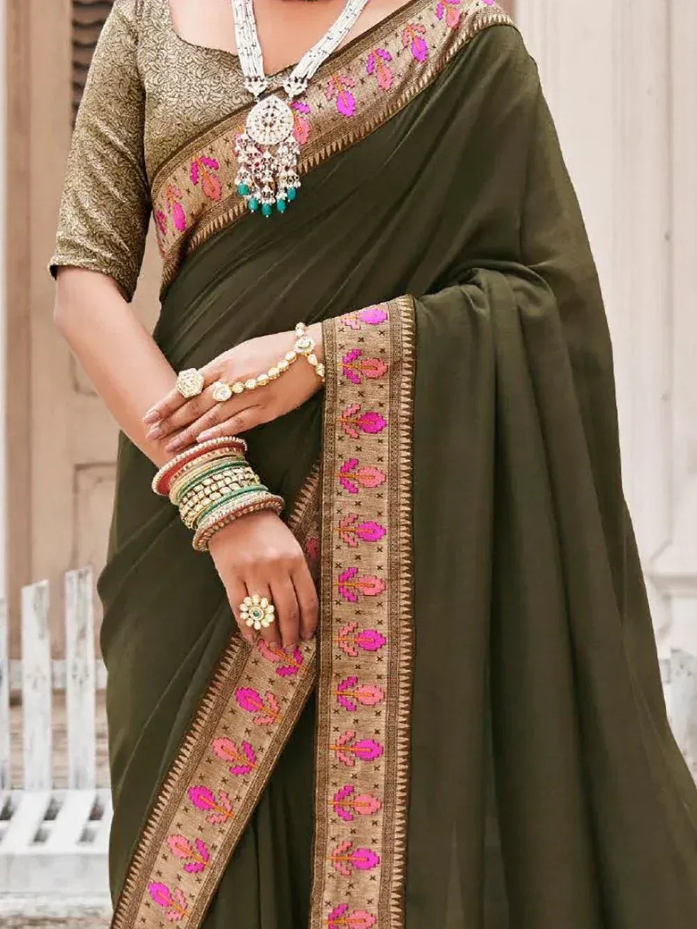 Olive green saree with pink floral embroidery, gold blouse, and traditional jewelry for Indian ethnic wear
