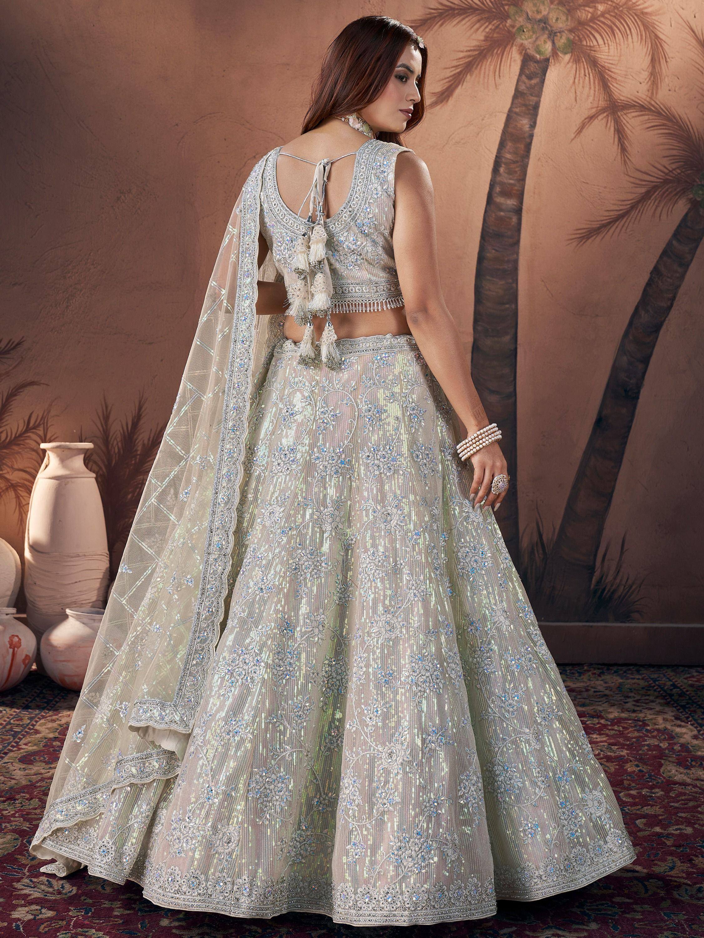 Elegant white lehenga choli with intricate embroidery and tassels, perfect for Indian weddings and festive occasions.