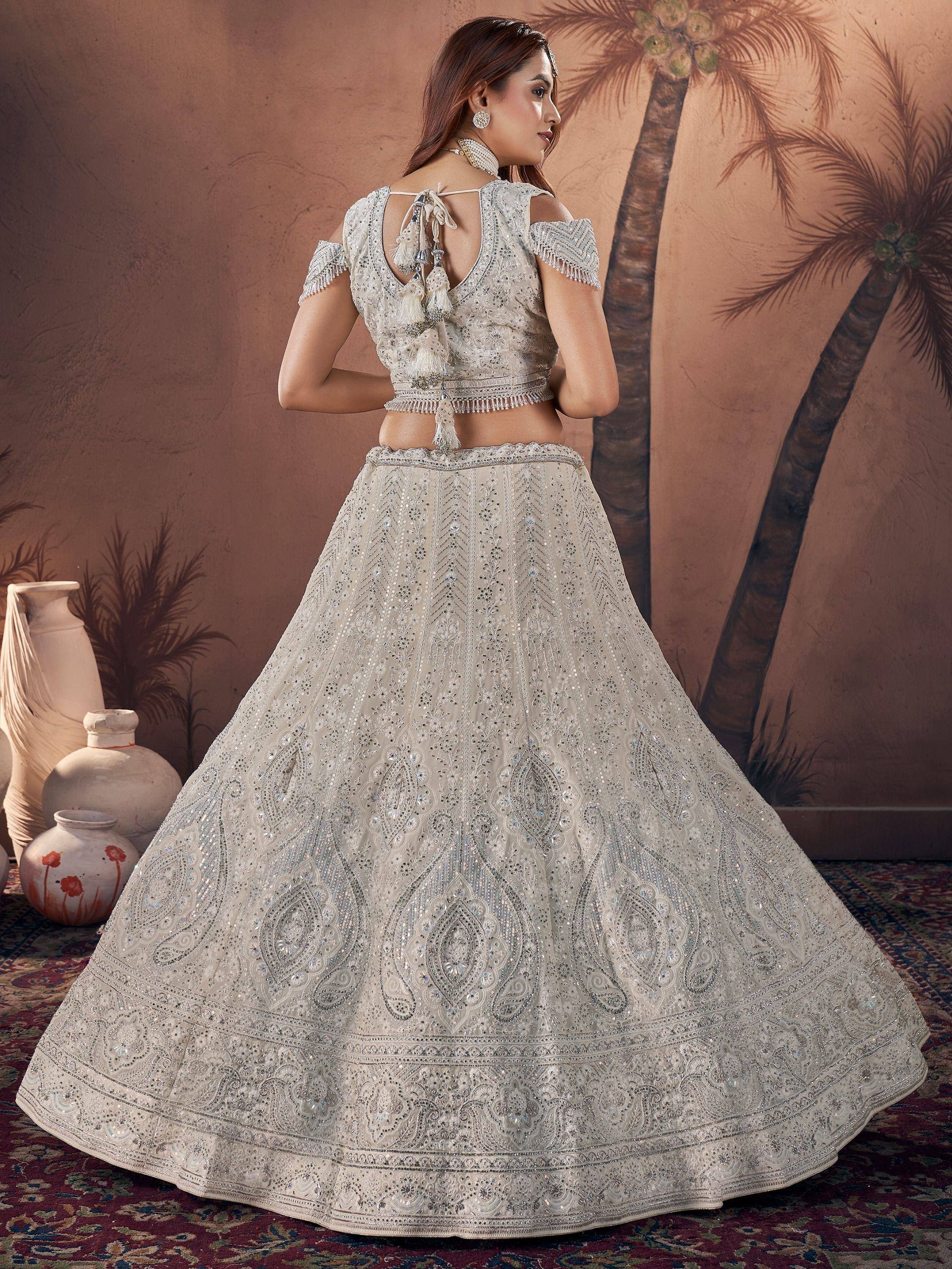Elegant ivory lehenga choli with intricate embroidery and tassel details, perfect for Indian weddings and festive occasions.