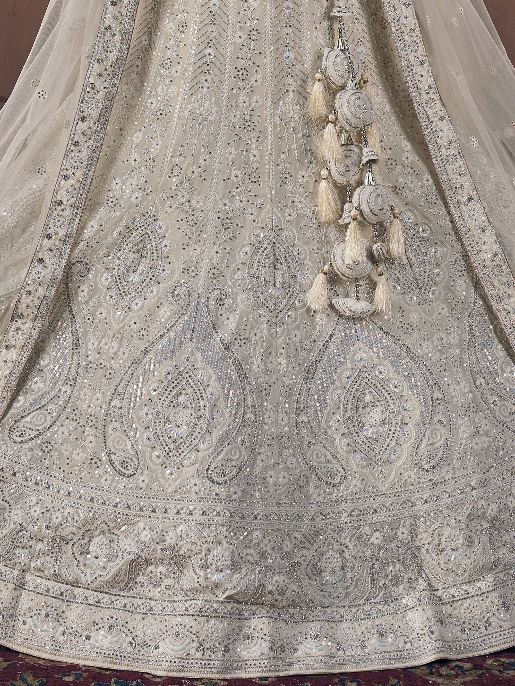 Elegant silver embroidered lehenga with intricate mirror work and tassel detailing, perfect for Indian weddings.