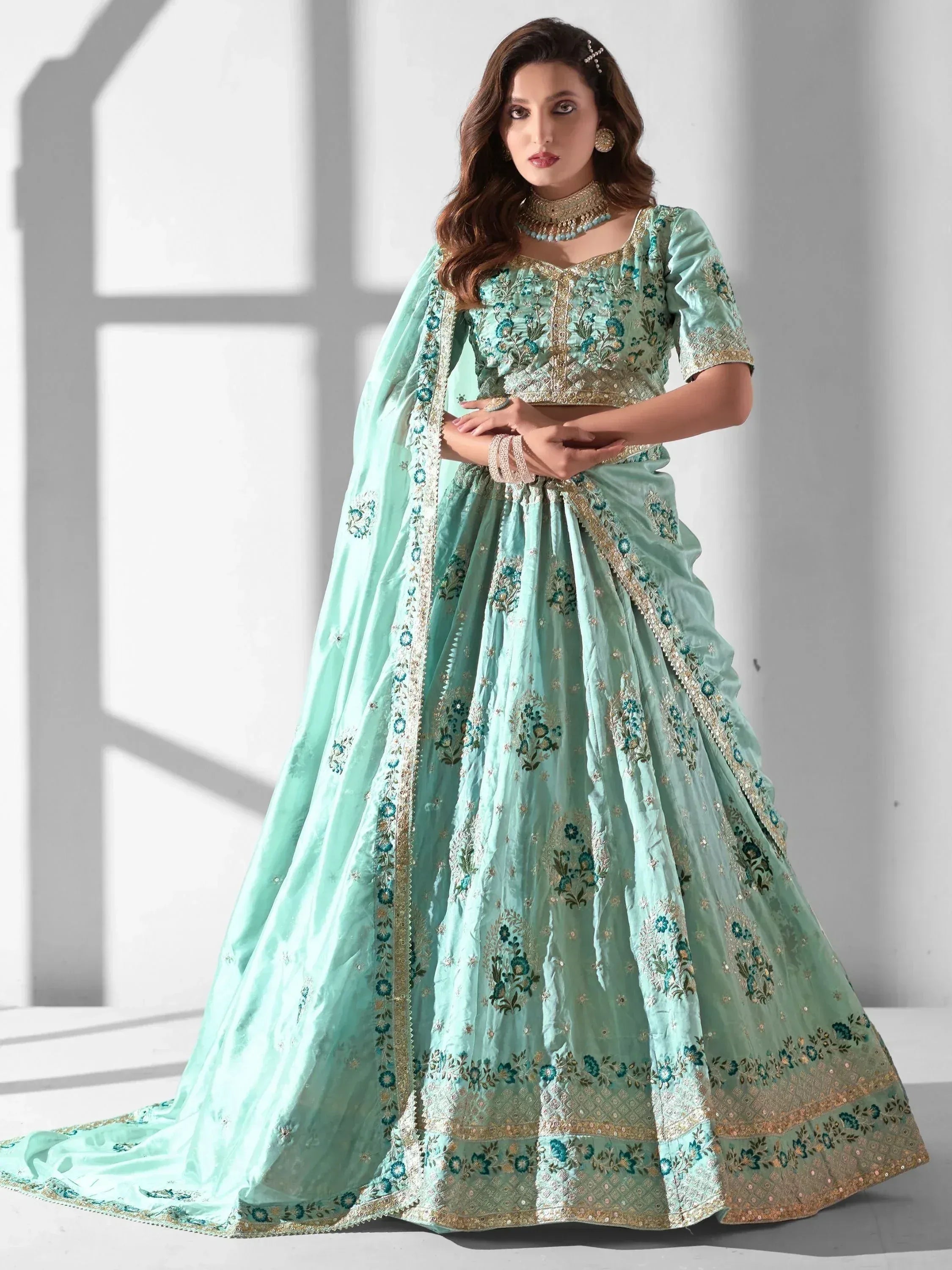 Mint green designer lehenga choli with floral embroidery and gold detailing, perfect for weddings and parties.