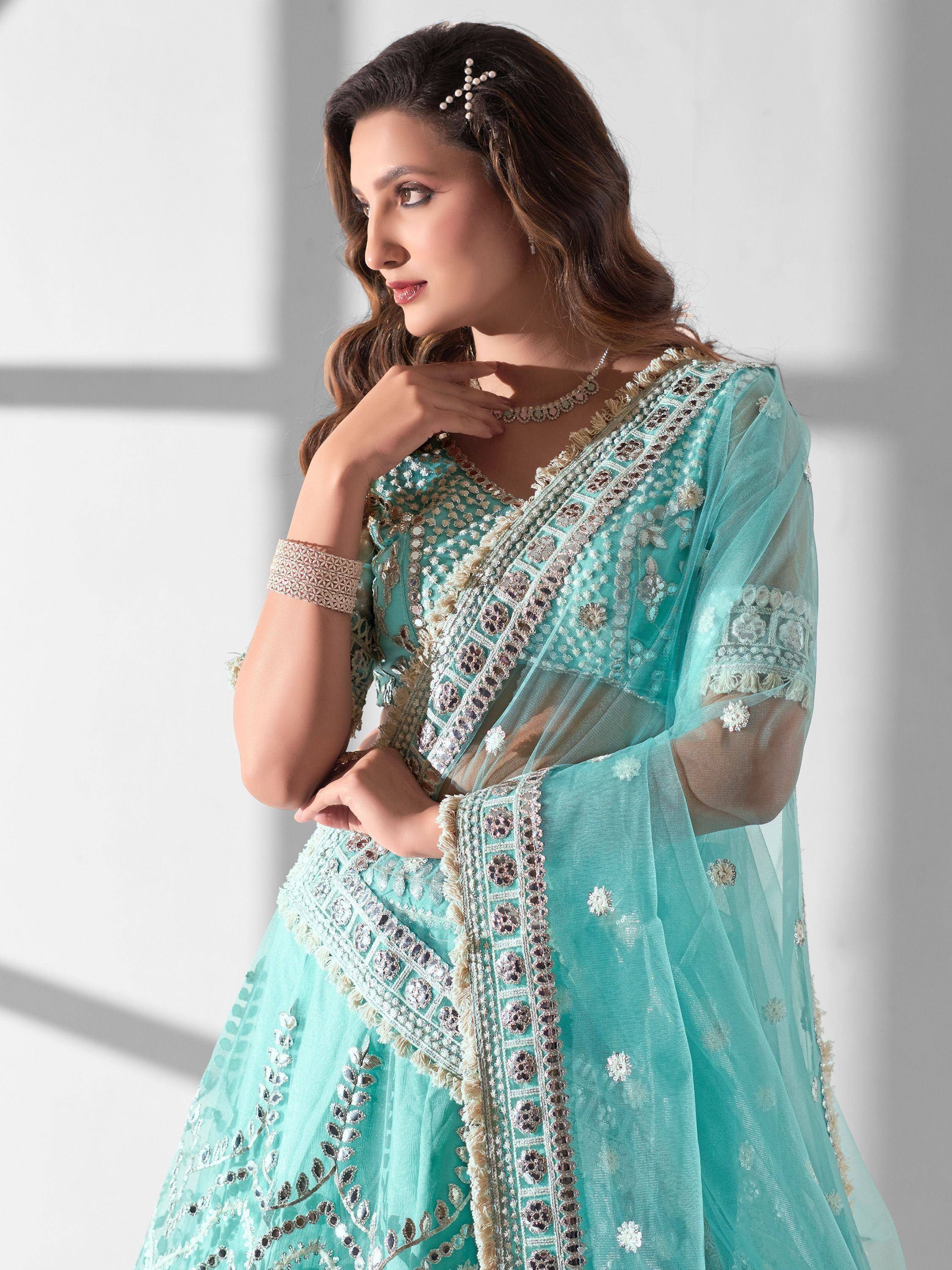 Elegant turquoise designer lehenga choli with intricate embroidery and sheer dupatta, perfect for Indian ethnic wear occasions.