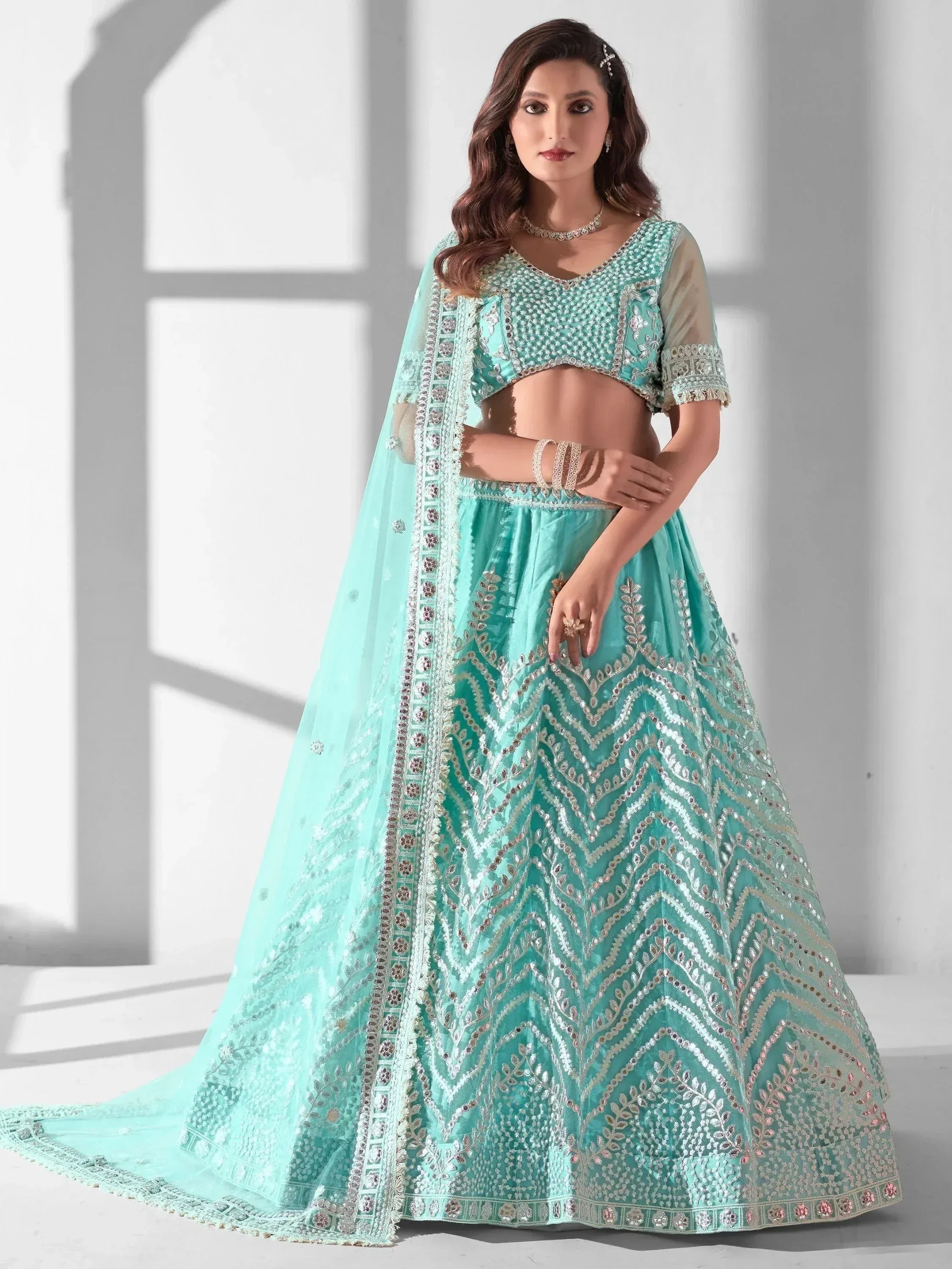Mint green designer lehenga choli with intricate silver embroidery and sheer dupatta, perfect for Indian weddings and festive occasions.