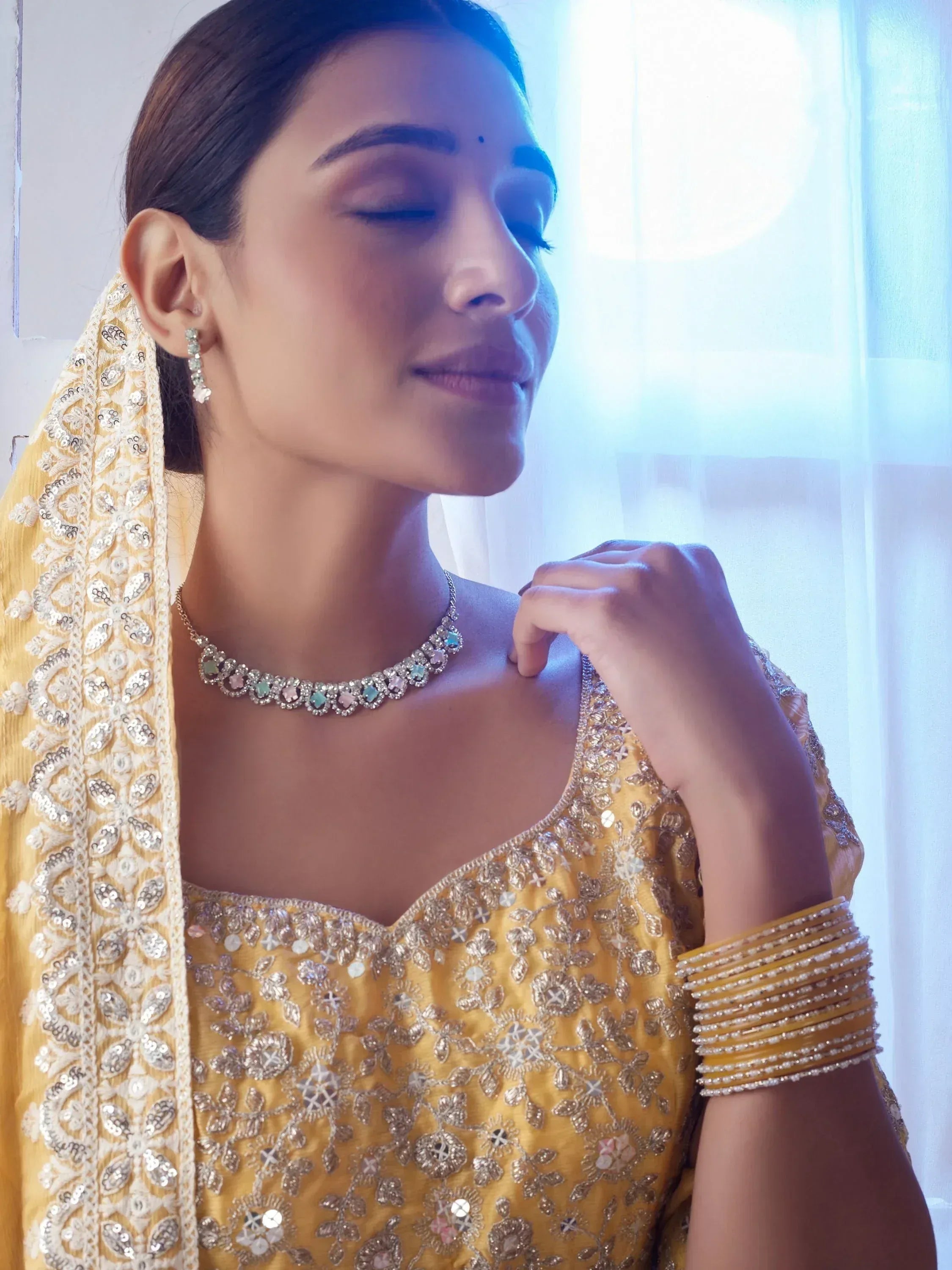 Elegant woman in yellow embroidered ethnic wear with statement necklace and bangles, perfect for Indian celebrations.