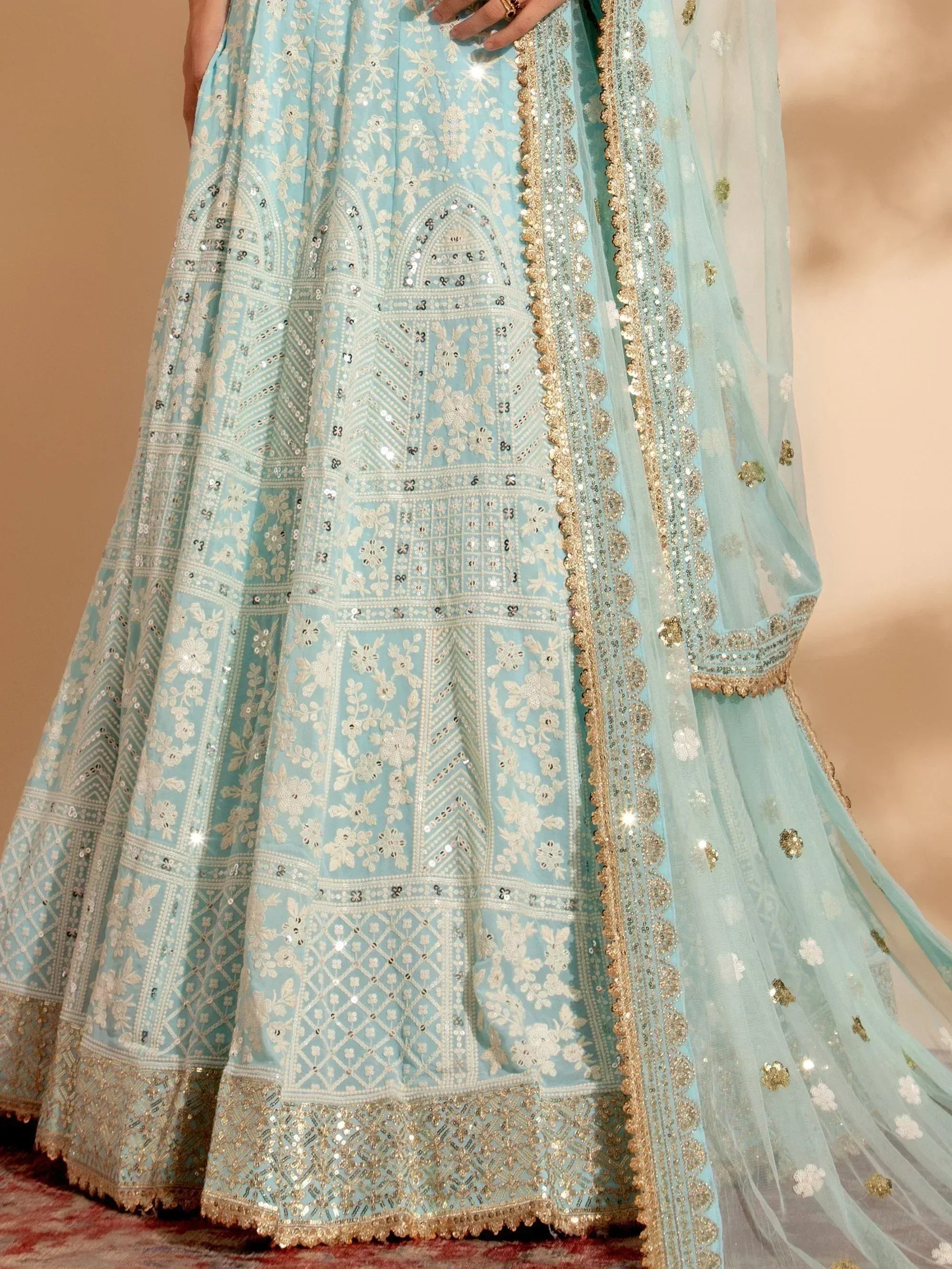 Light blue designer lehenga choli with intricate floral embroidery and gold sequin detailing, perfect for weddings and festive occasions.
