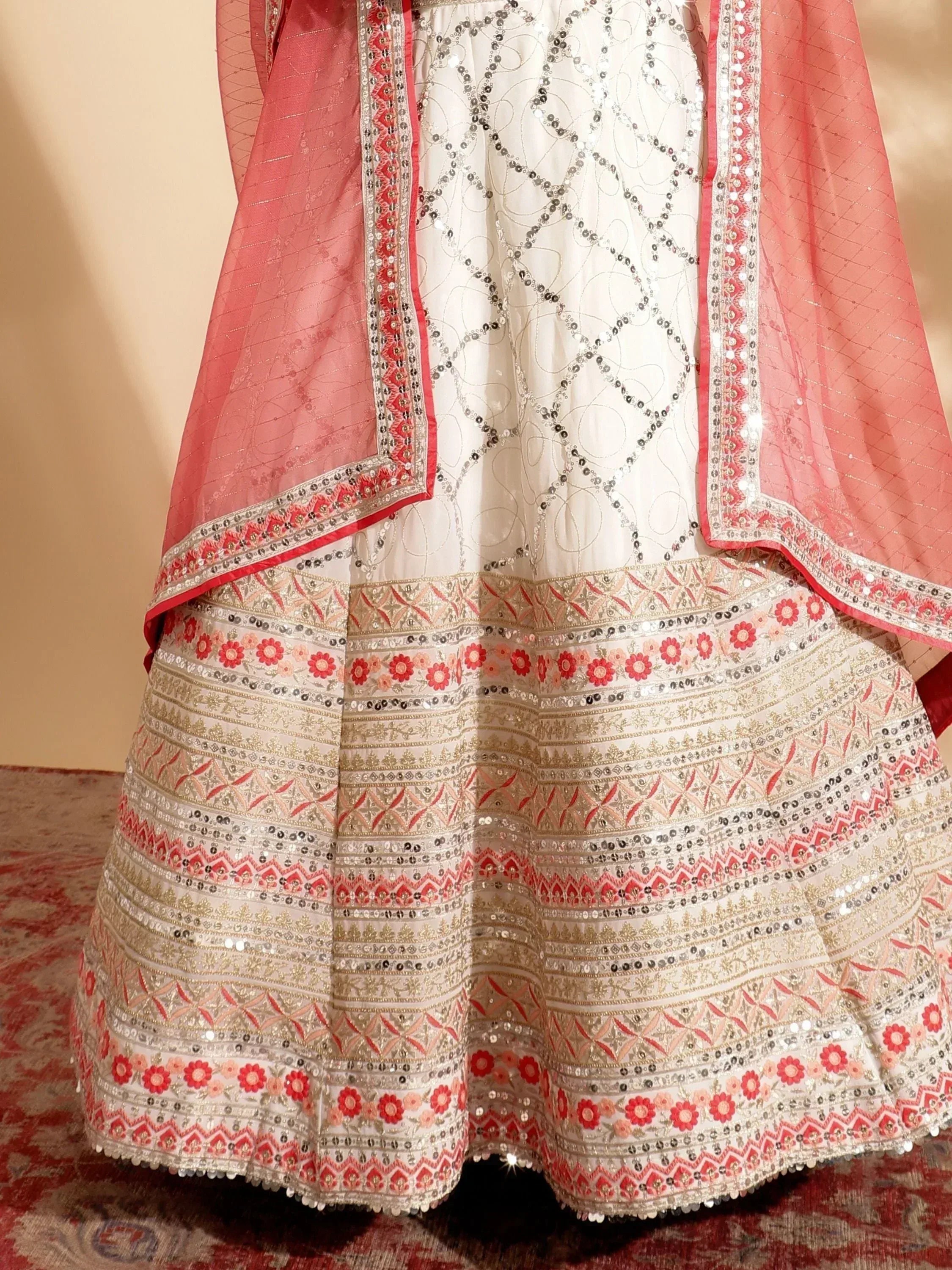 White and coral Indian lehenga choli with intricate embroidery and mirror work, perfect for weddings and festivals.