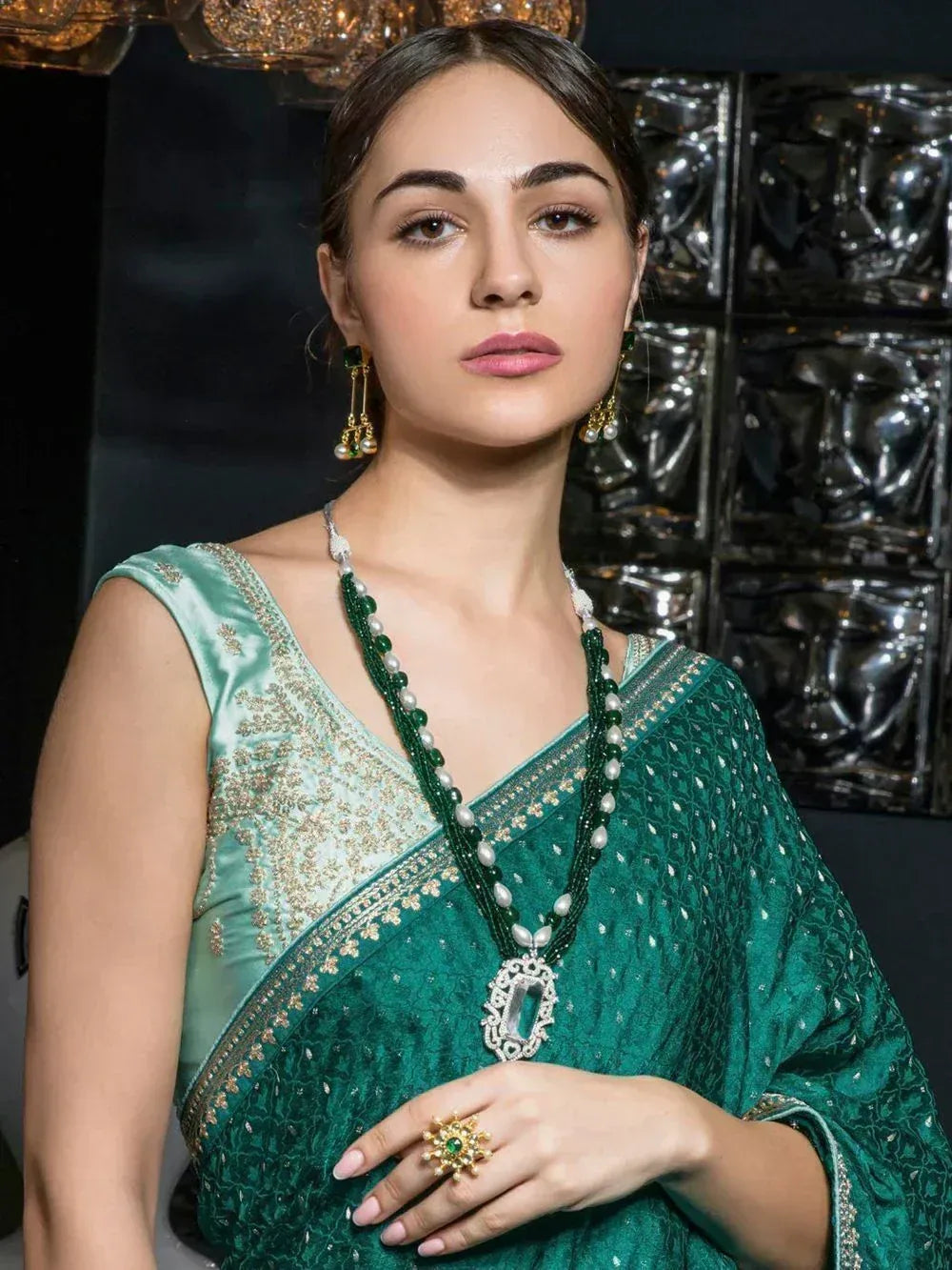 Woman in elegant green embroidered saree with matching jewelry, showcasing Indian ethnic wear