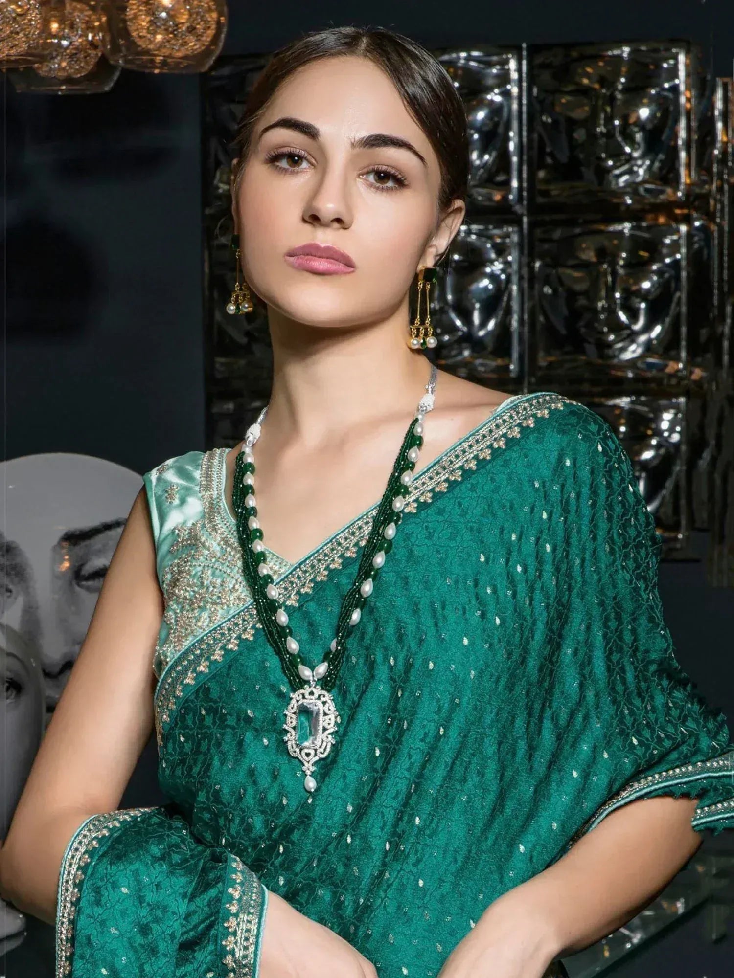 Emerald green designer saree with gold embroidery and pearl jewelry, perfect for Indian ethnic occasions.