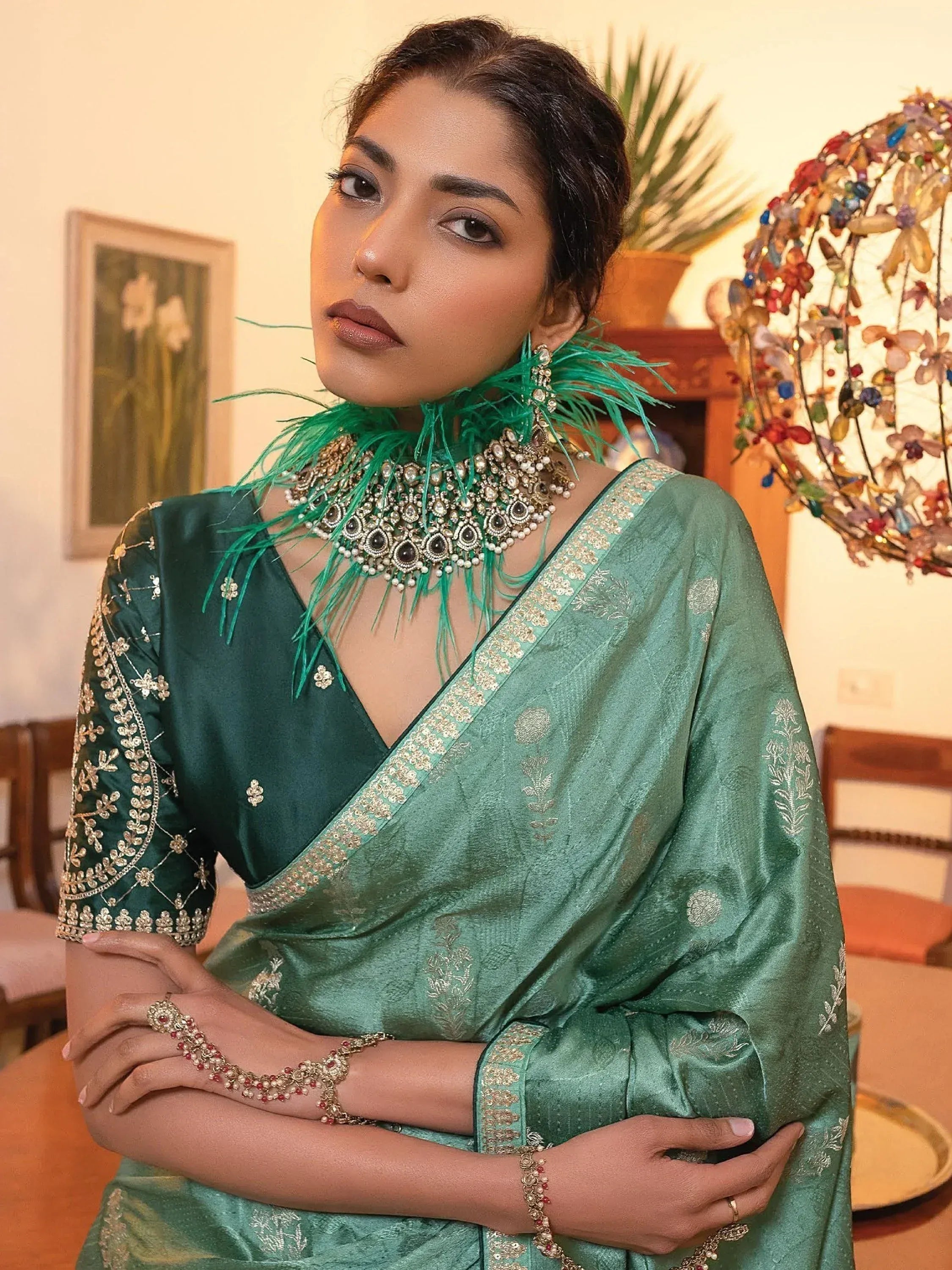 Emerald green saree with gold embroidery, feathered necklace, and traditional Indian jewelry for festive occasions