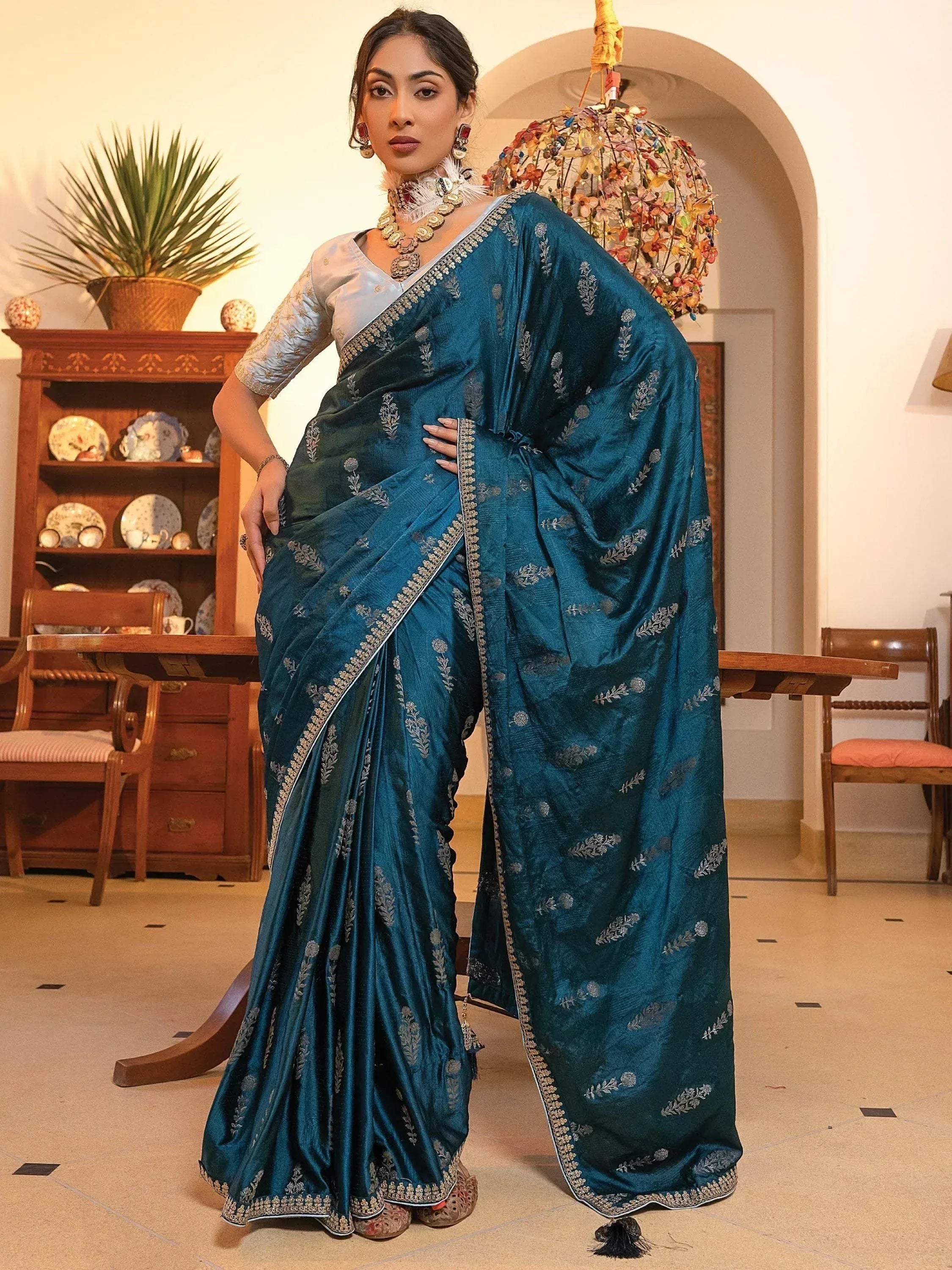 Teal embroidered saree with silver detailing, paired with a light blue blouse, perfect for Indian ethnic occasions.