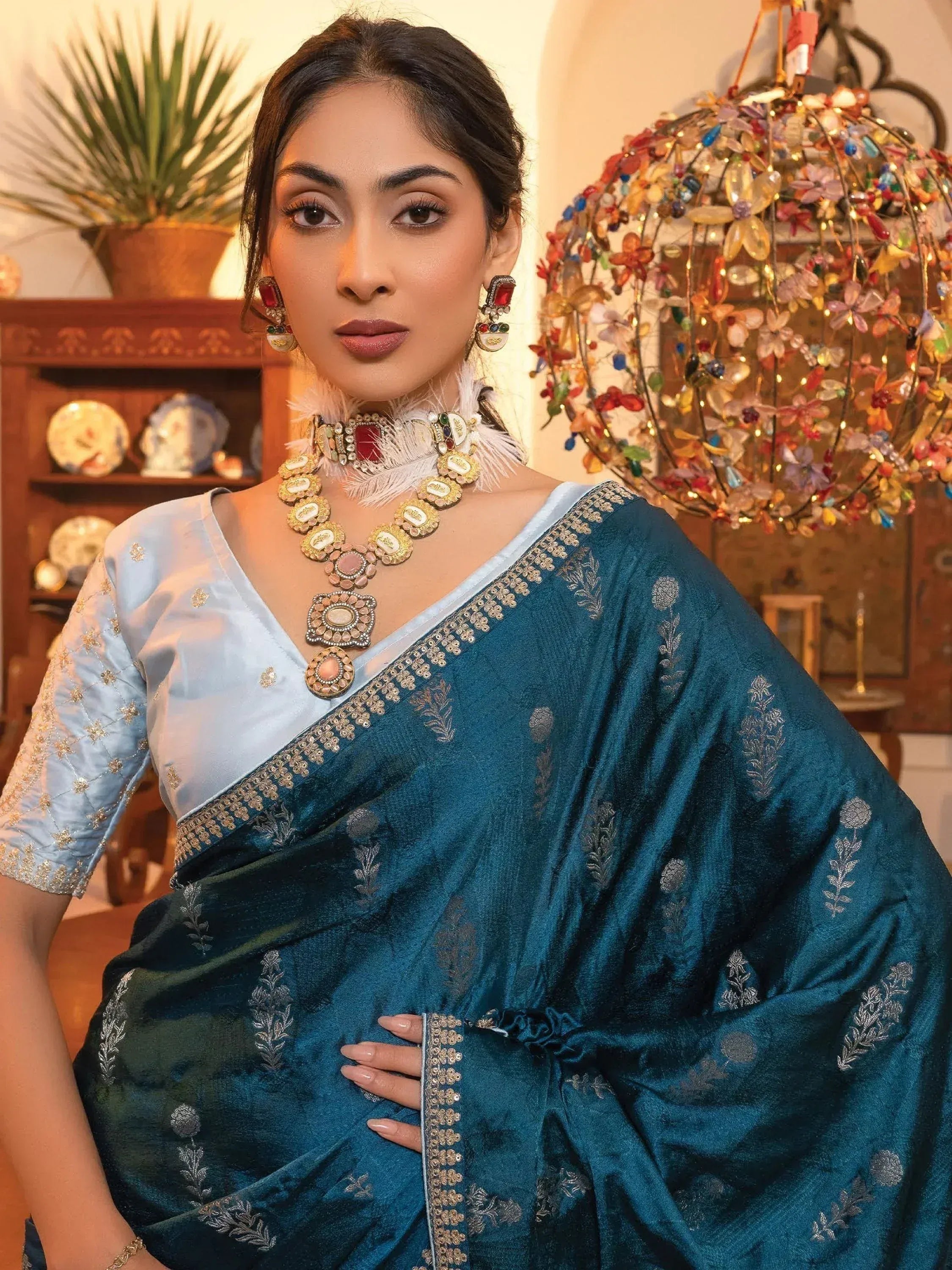 Woman in teal embroidered saree with gold detailing and statement jewelry, Indian ethnic wear