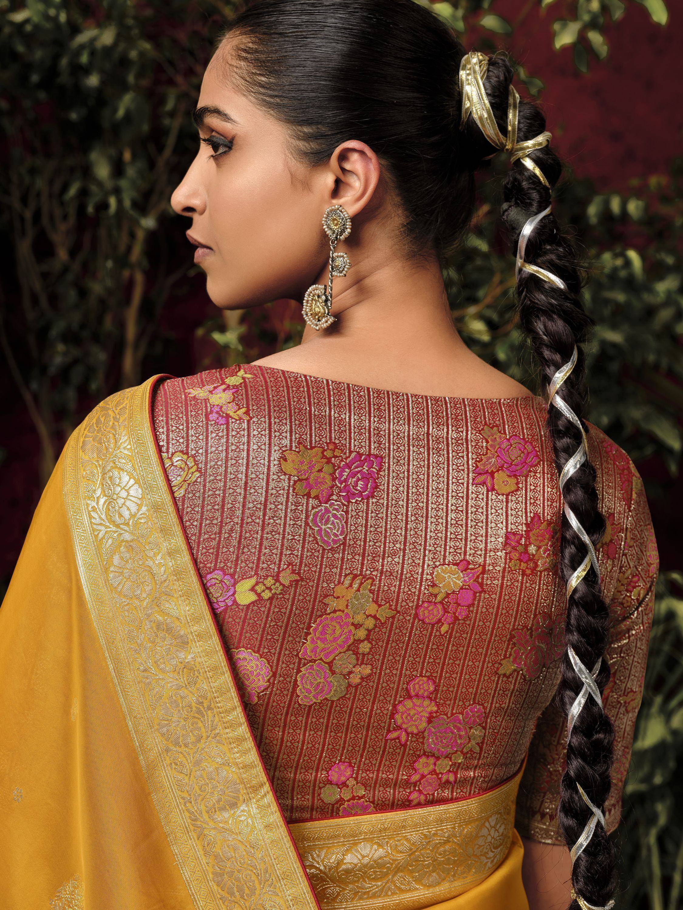 Elegant woman in maroon and gold floral saree with intricate back design and braided hair