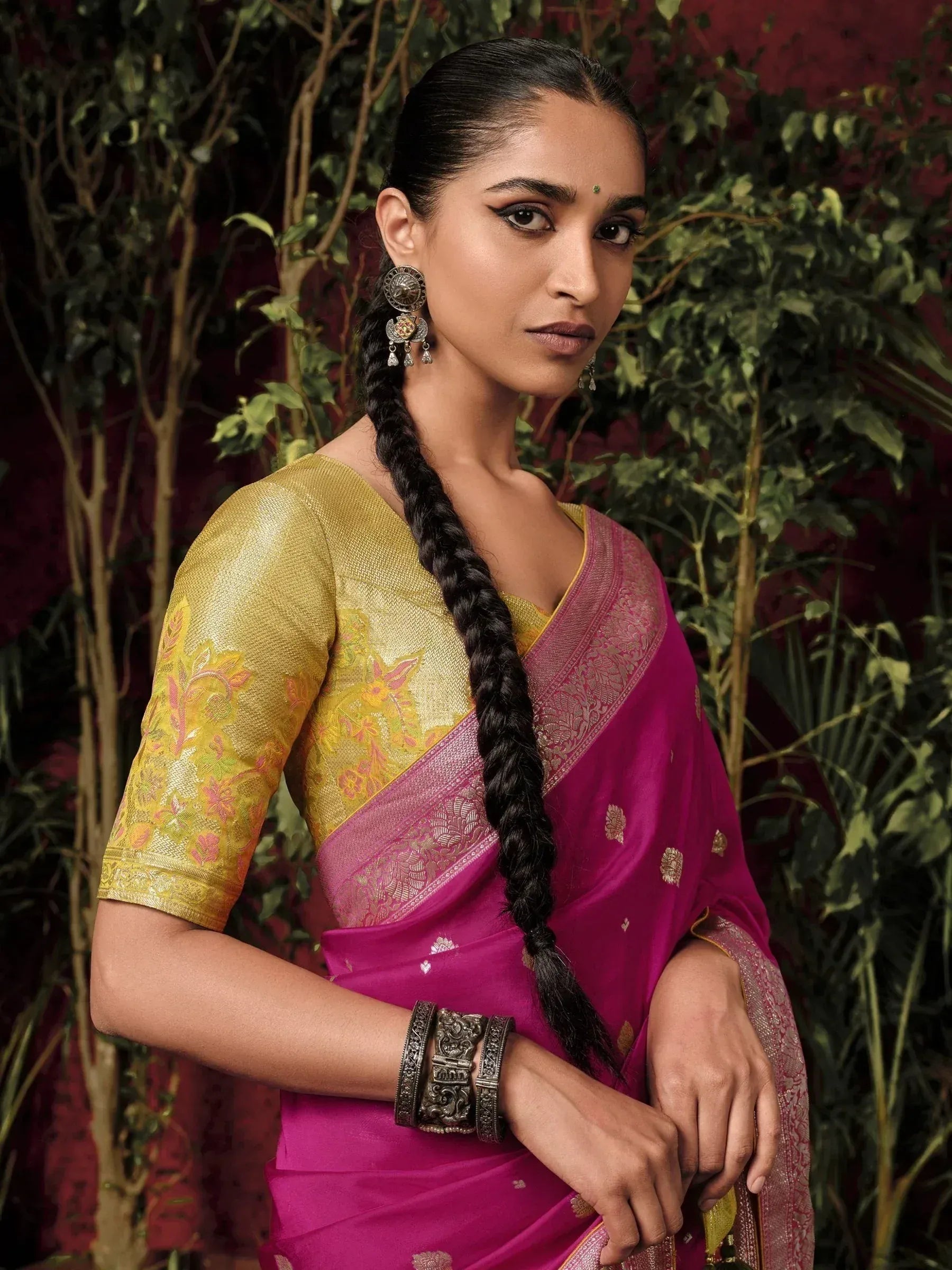 Woman in vibrant pink saree with gold blouse, traditional Indian ethnic wear, floral embroidery, and temple jewelry