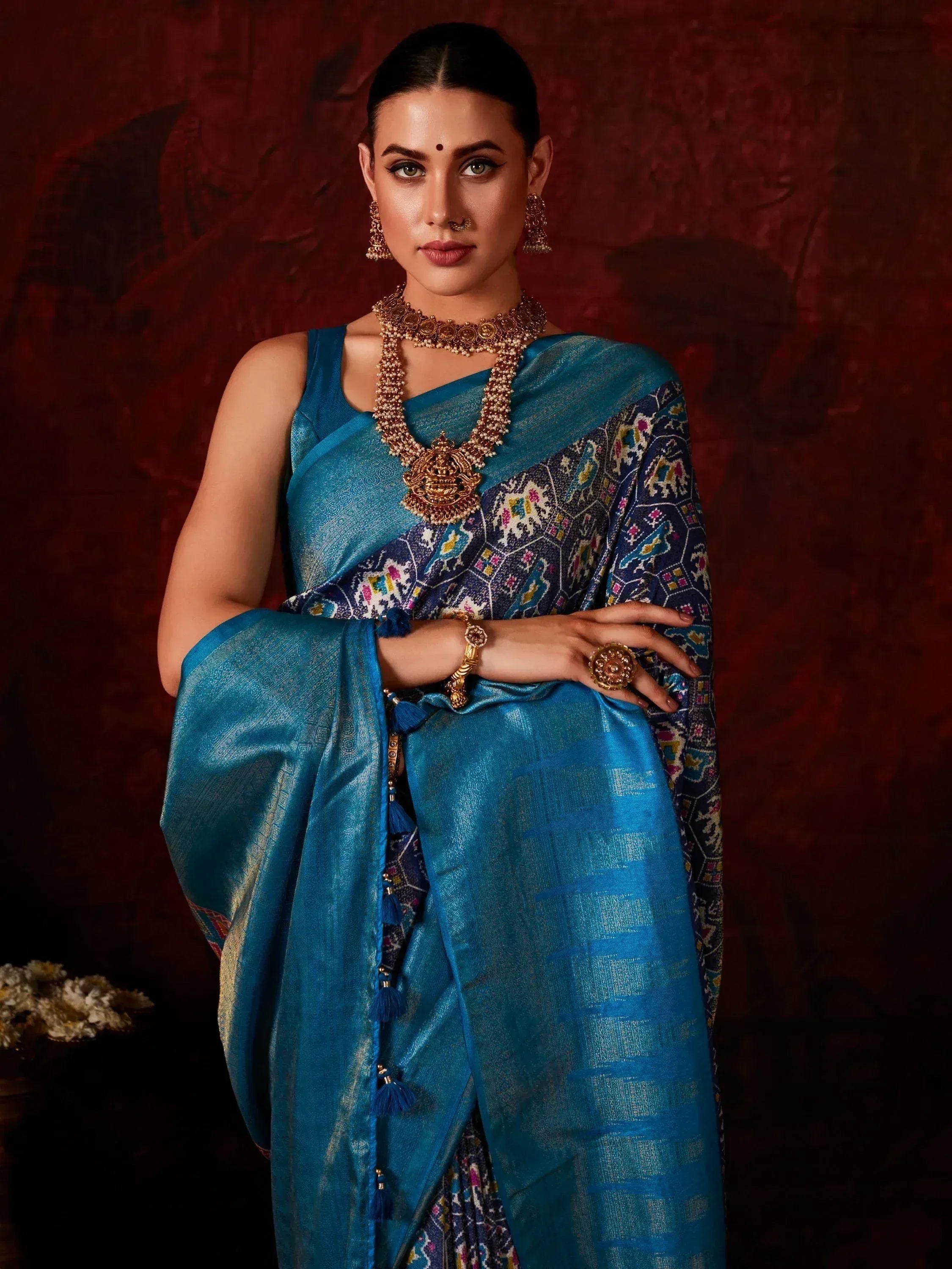 Woman in blue designer saree with intricate embroidery and gold jewelry, perfect for Indian ethnic wear.