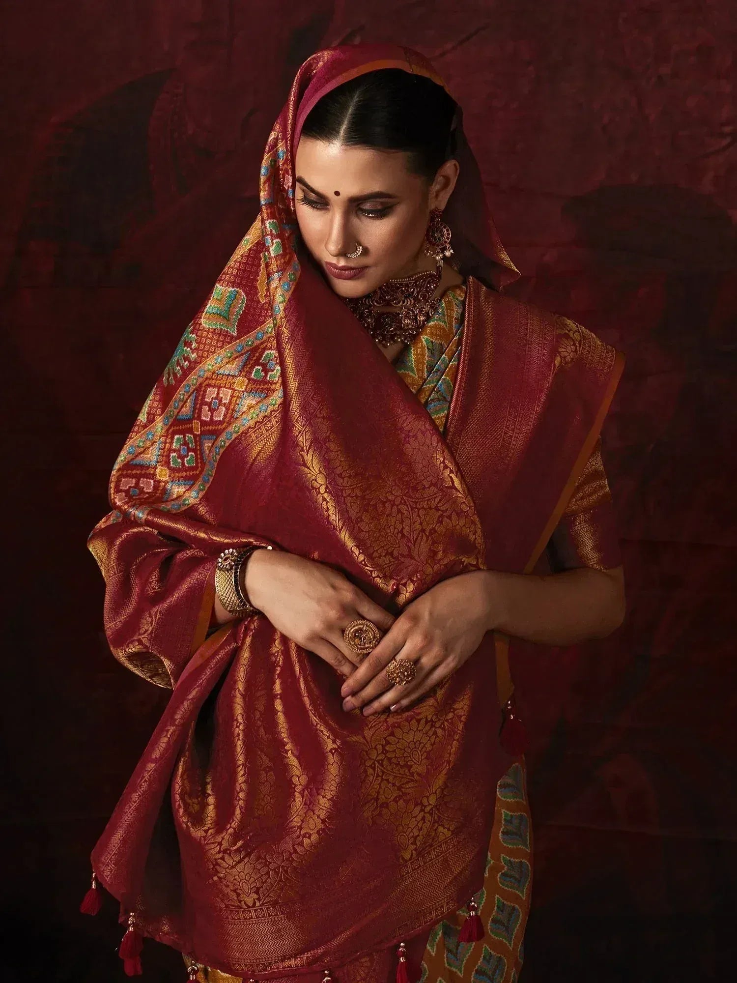 Elegant maroon and gold designer saree with intricate embroidery and traditional jewelry