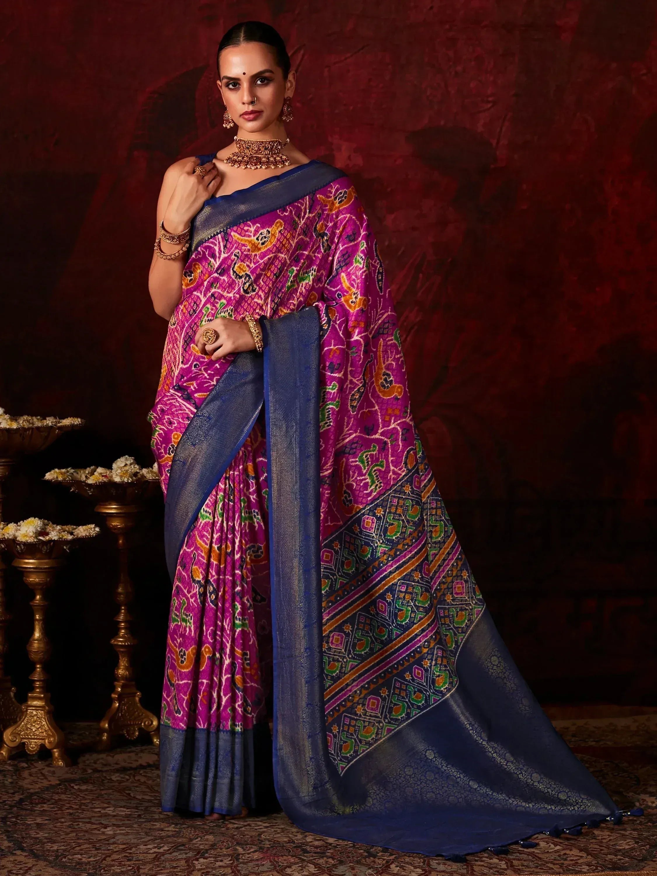 Woman in vibrant purple and blue printed saree with gold jewelry, ethnic Indian wear