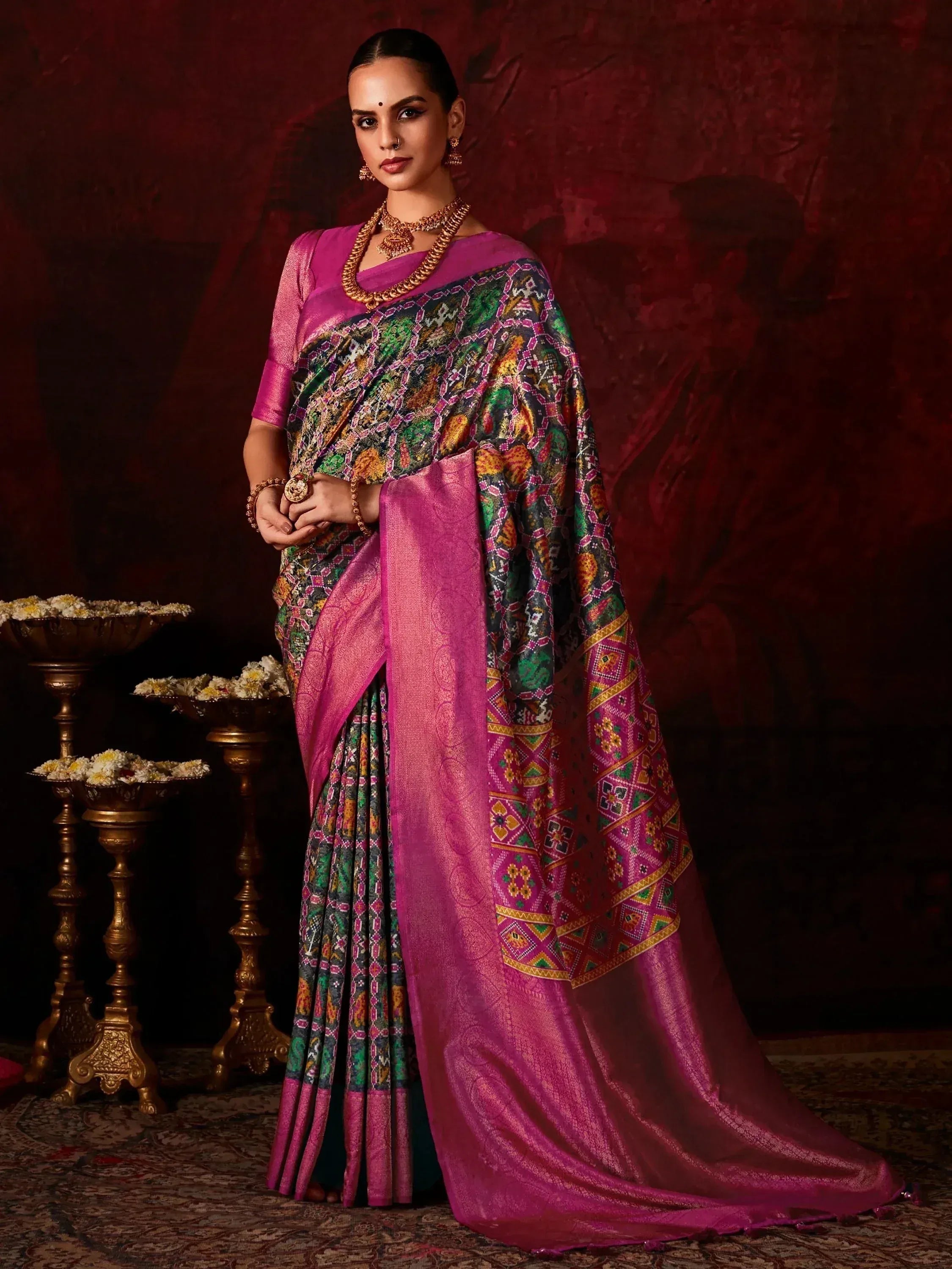 Woman in vibrant pink and multicolor printed saree with gold jewelry, traditional Indian ethnic wear