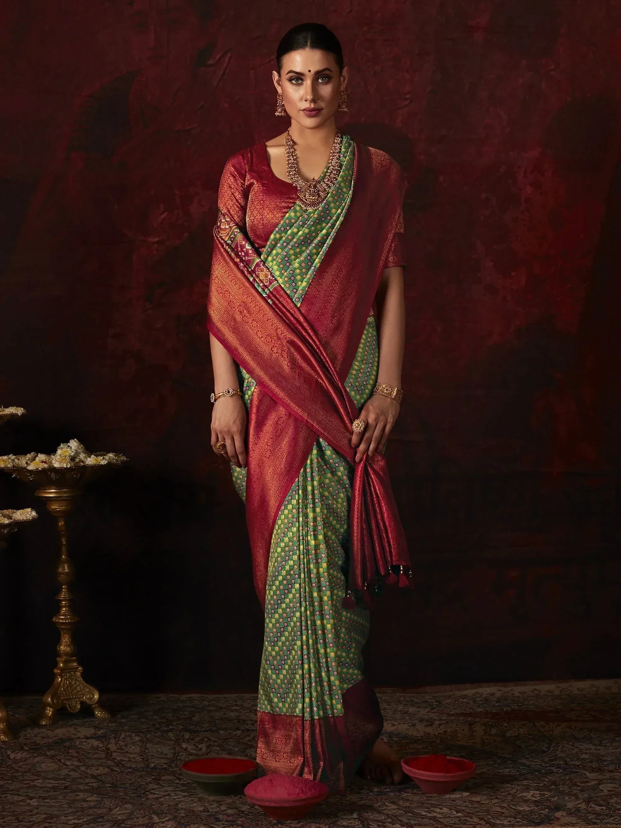 Woman in maroon and green designer saree with gold jewelry, traditional Indian ethnic wear