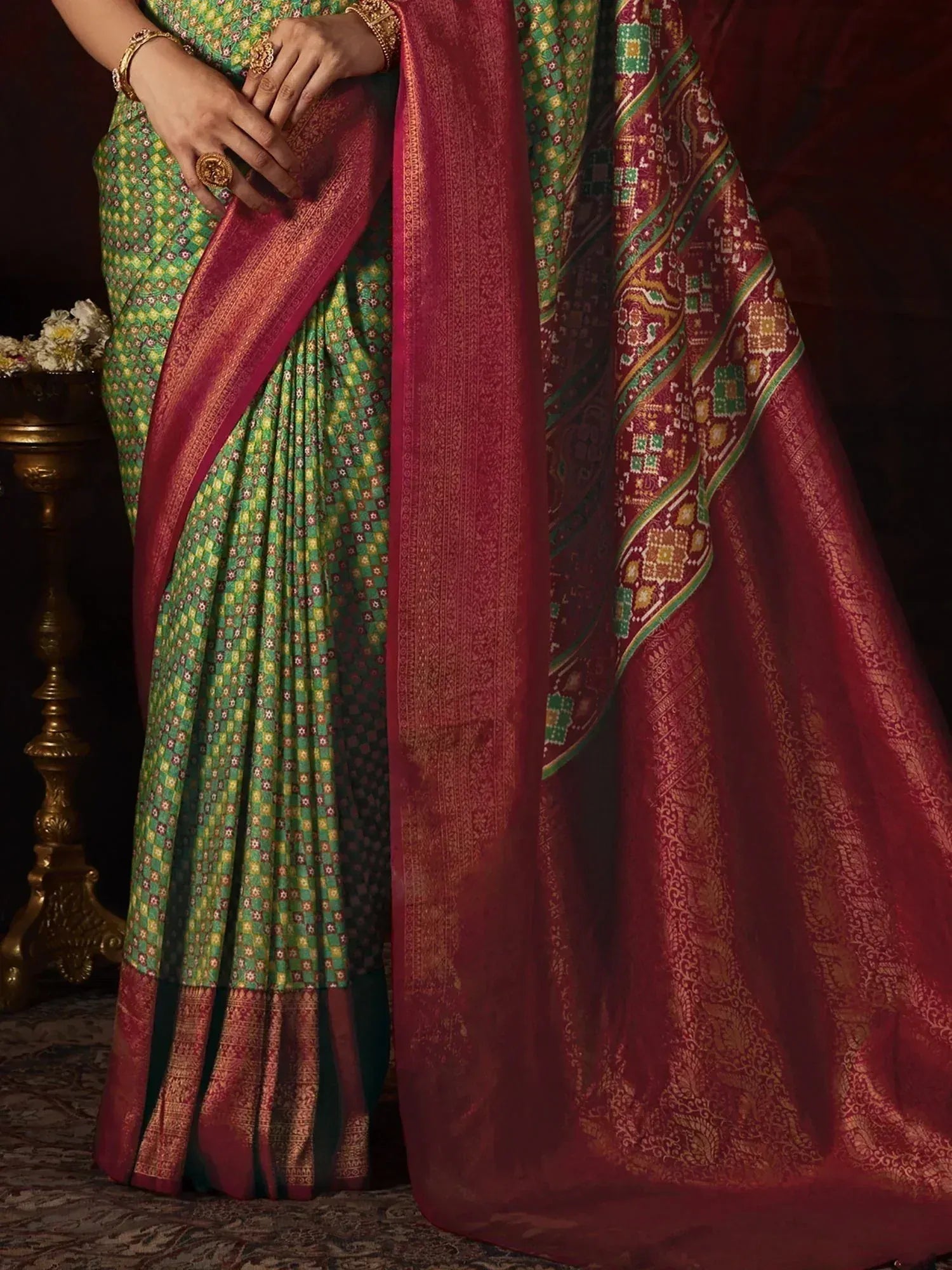 Green and maroon designer saree with intricate patterns and gold zari border, perfect for ethnic occasions.