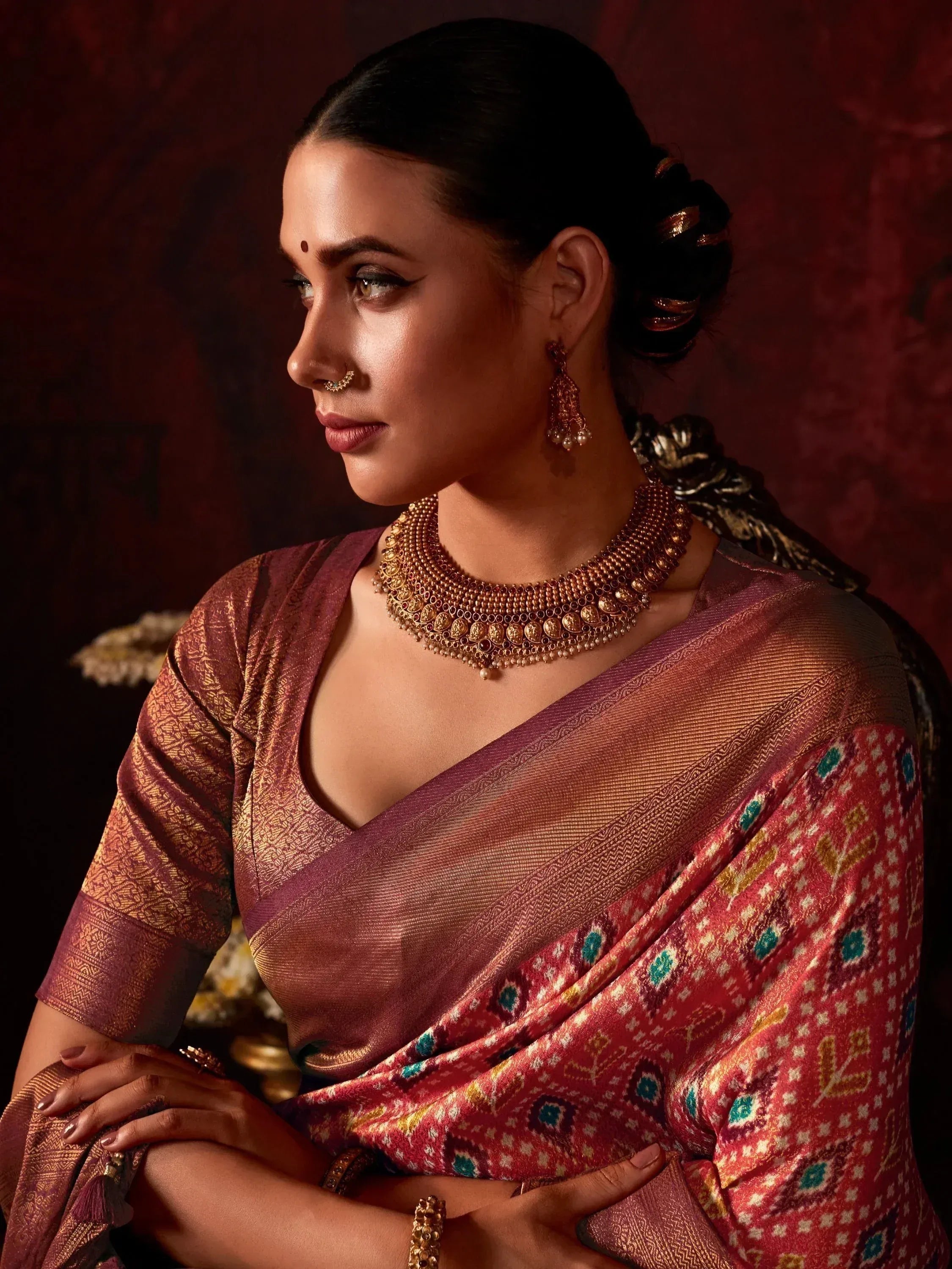 Elegant woman in maroon and gold designer saree with traditional jewelry, perfect for Indian ethnic occasions.