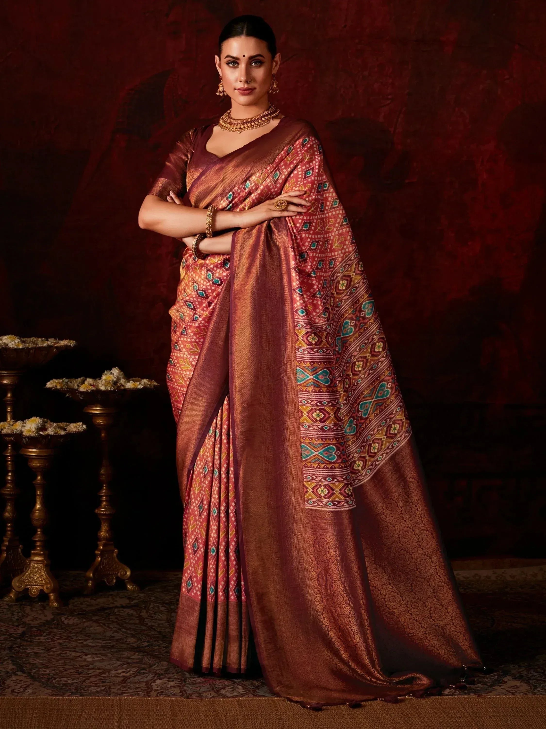 Woman in elegant maroon saree with intricate geometric patterns and gold jewelry, perfect for Indian ethnic wear occasions.