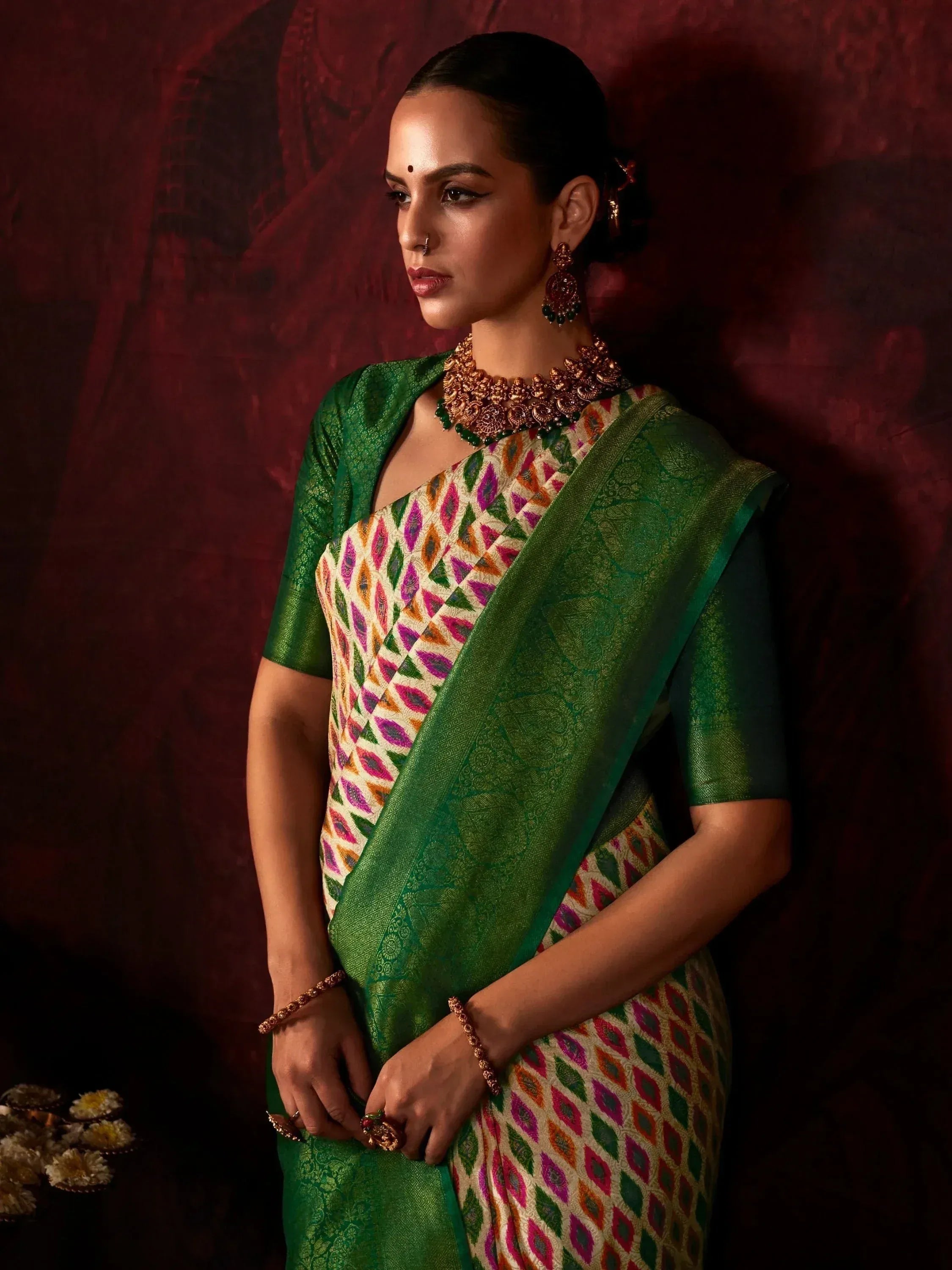 Woman in vibrant green and multicolor patterned saree with gold jewelry, ethnic Indian wear