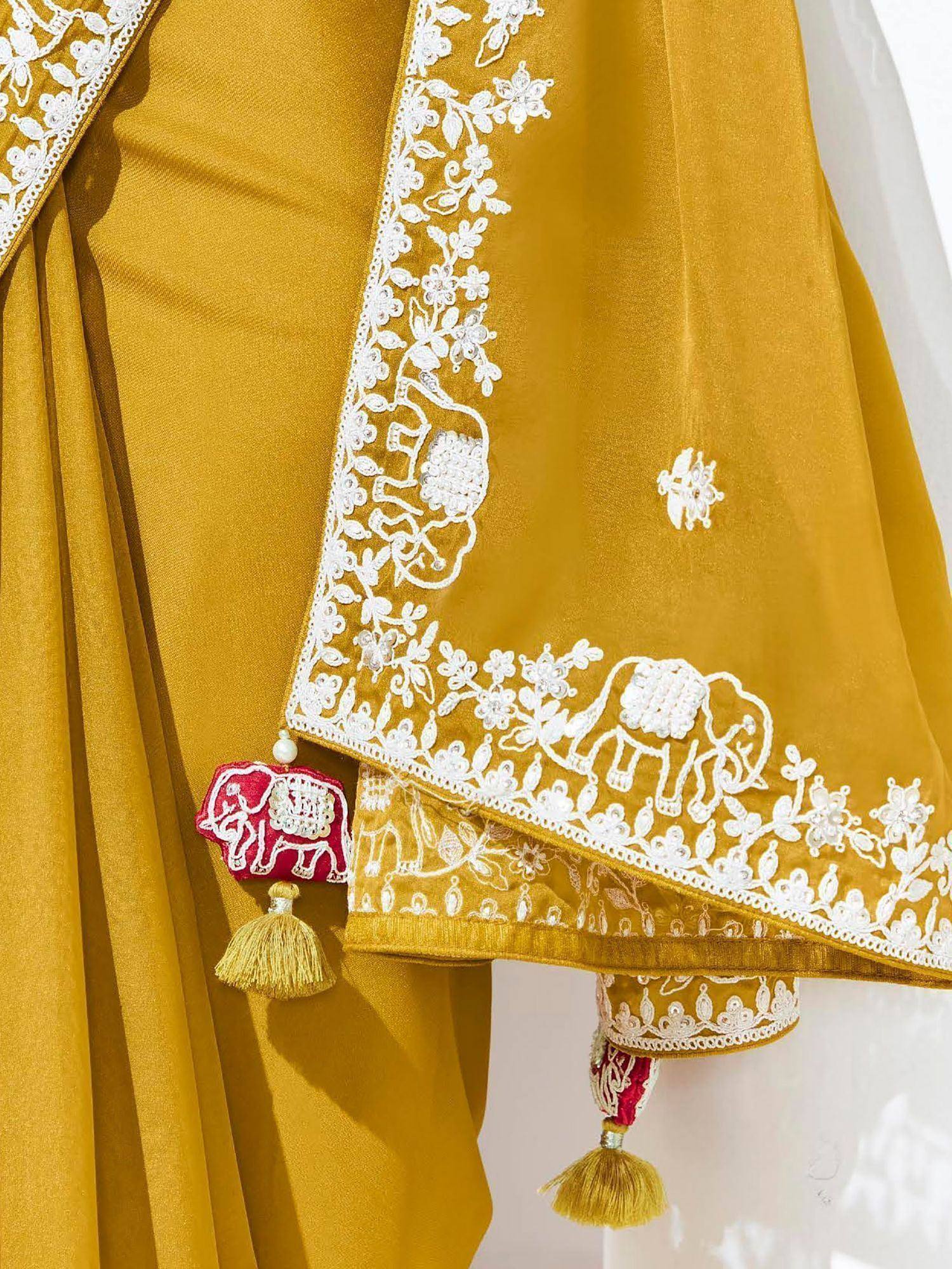 Mustard yellow ethnic wear with white floral and elephant embroidery, red tassels, perfect for Indian occasions.