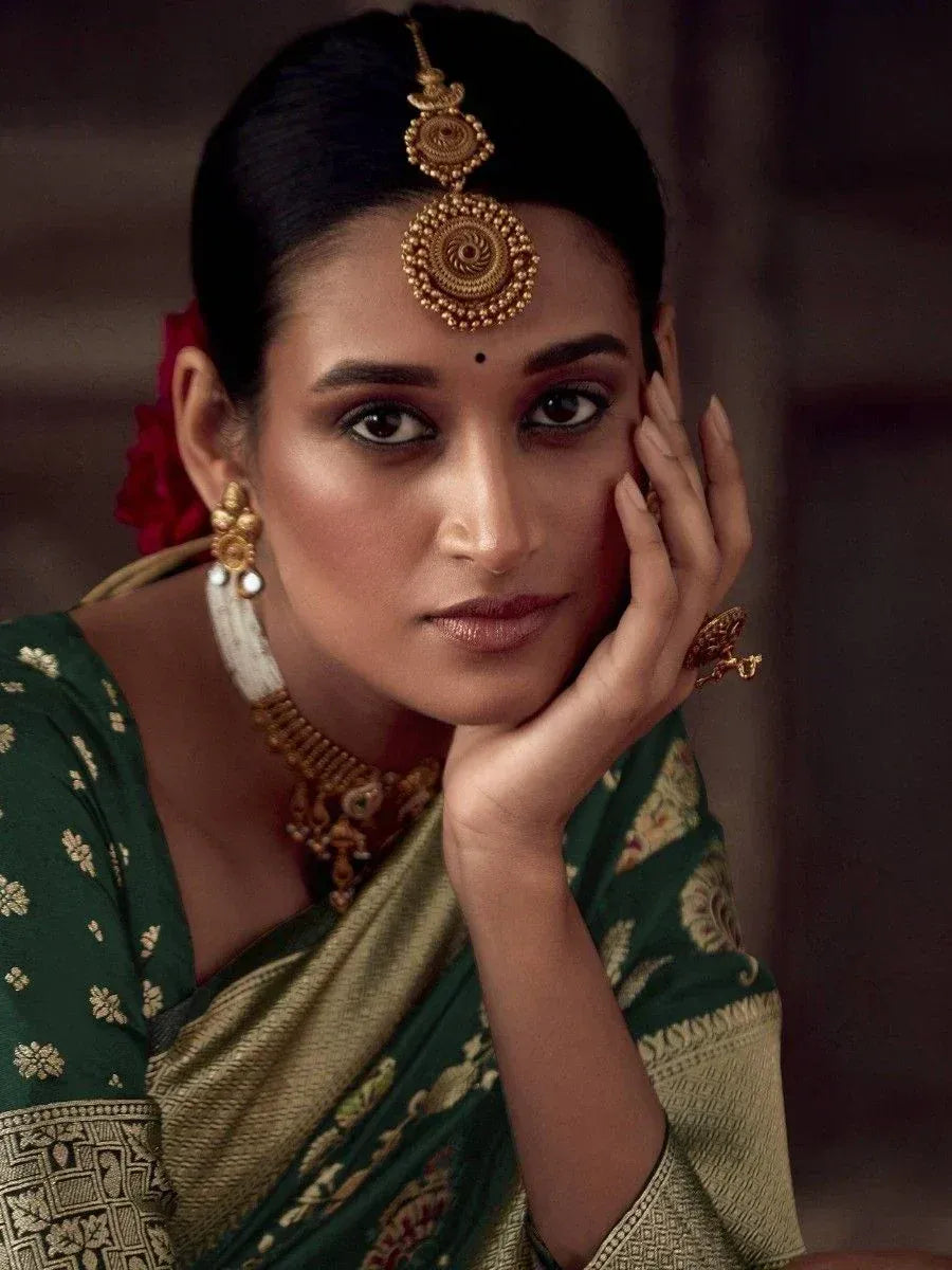 Woman in green and gold ethnic saree with traditional jewelry and maang tikka