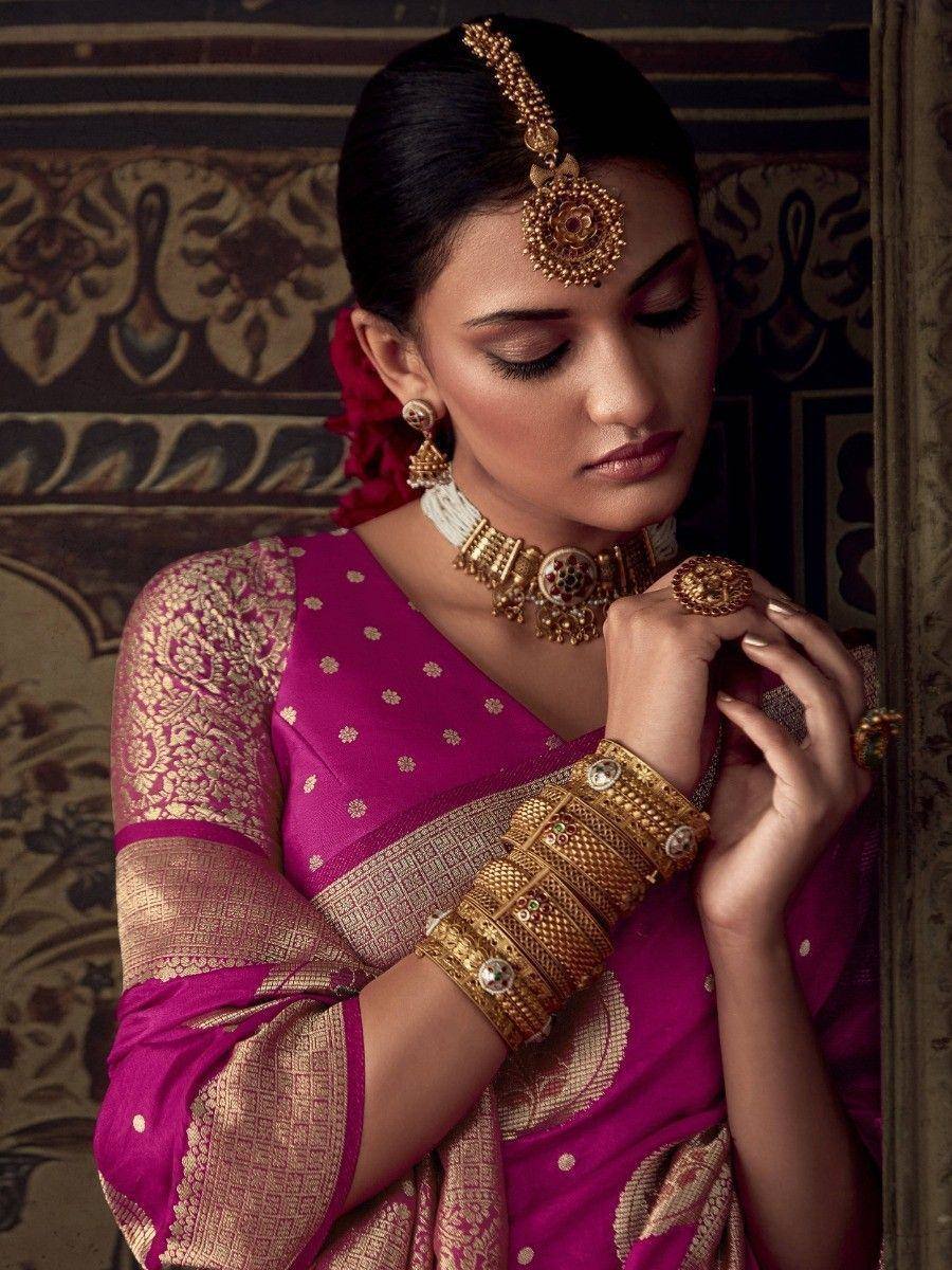 Woman in magenta ethnic saree with gold embroidery and traditional Indian jewelry