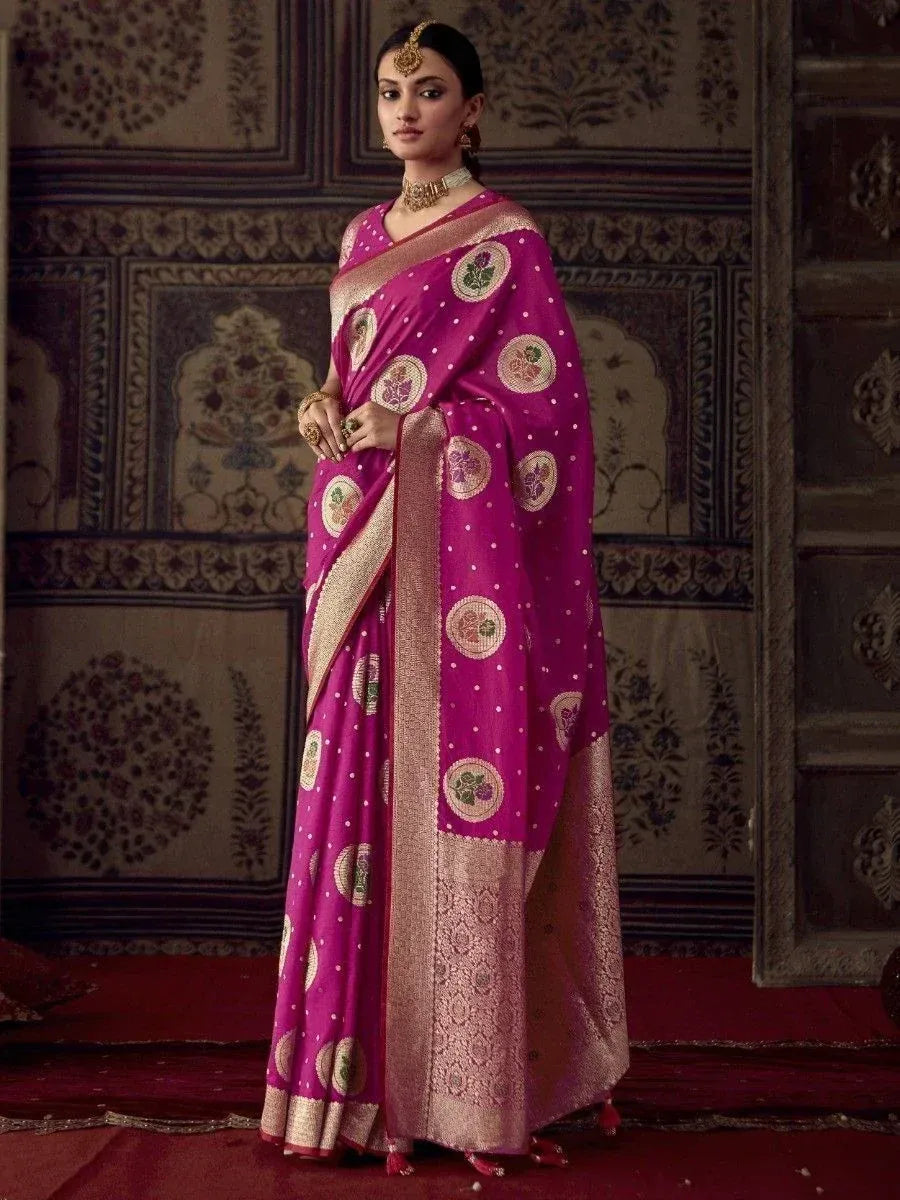 Vibrant magenta designer saree with floral motifs and gold border, styled with traditional jewelry for ethnic occasions