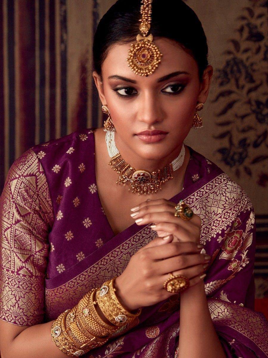 Woman in purple designer saree with gold jewelry, traditional Indian ethnic wear