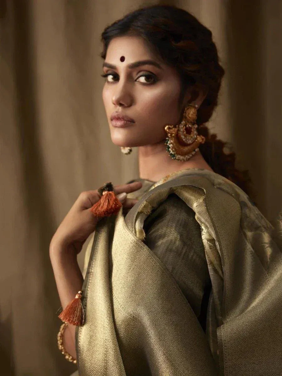 Woman in elegant gold saree with tassel details and traditional jewelry, showcasing Indian ethnic wear