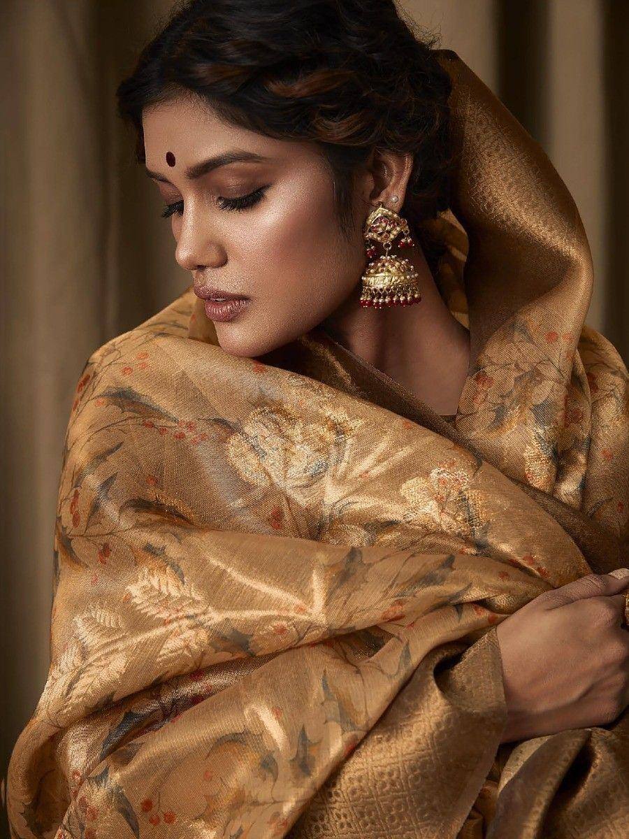 Elegant woman in golden floral saree with traditional jhumka earrings, showcasing Indian ethnic wear