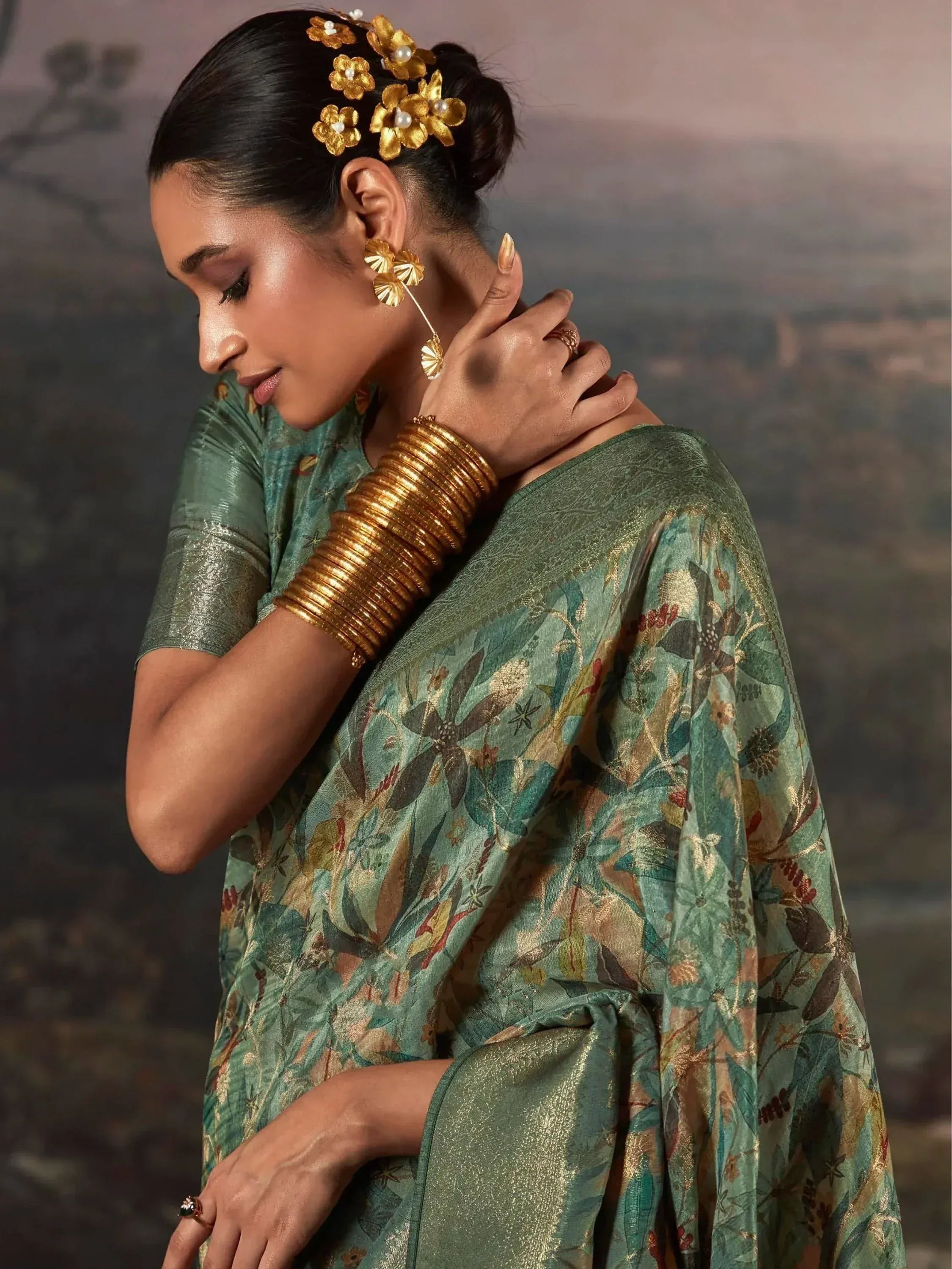 Elegant woman in green floral saree with gold jewelry, showcasing Indian ethnic wear