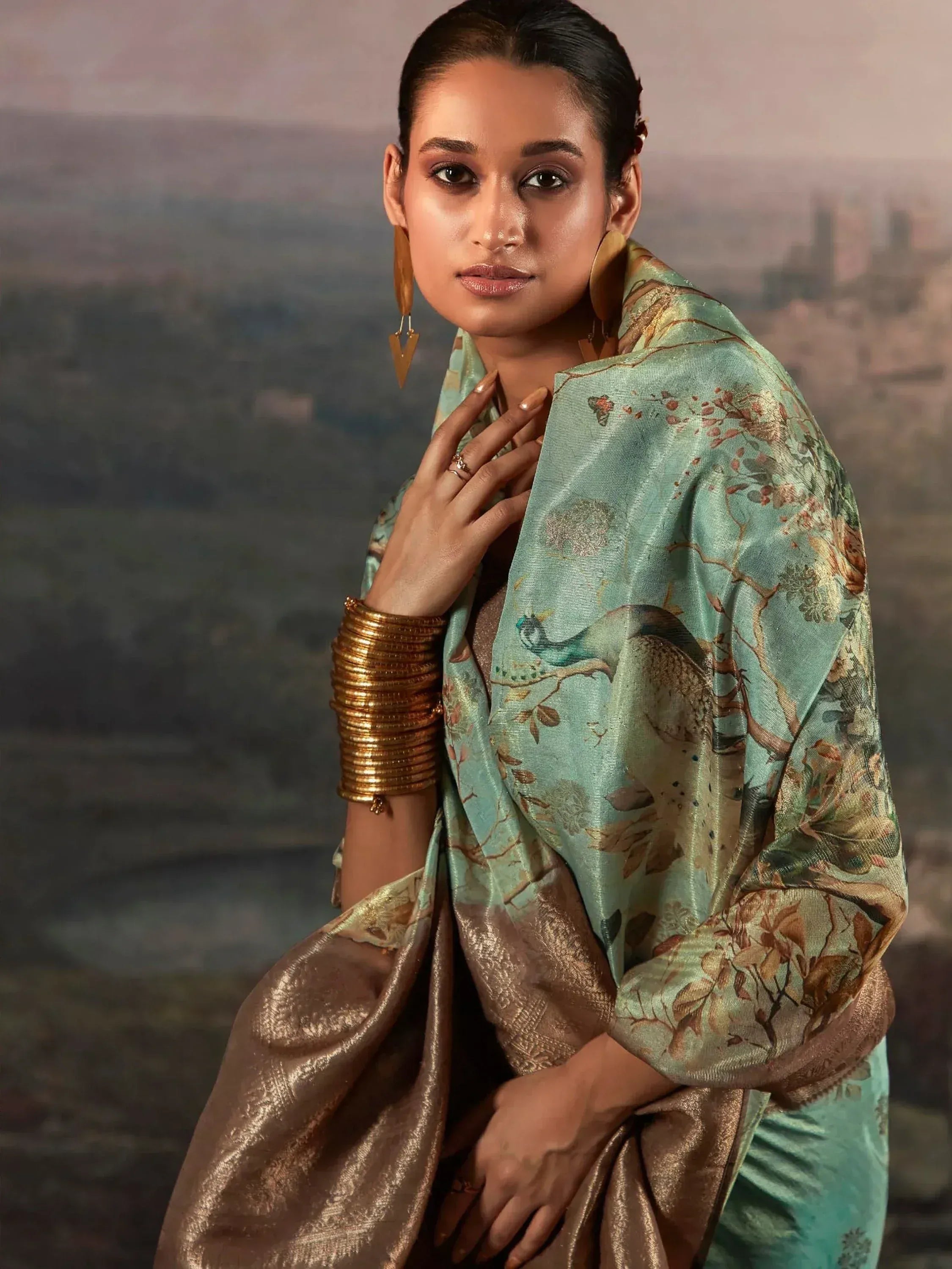 Elegant woman in mint green saree with peacock print, gold blouse, and traditional jewelry for Indian ethnic wear.