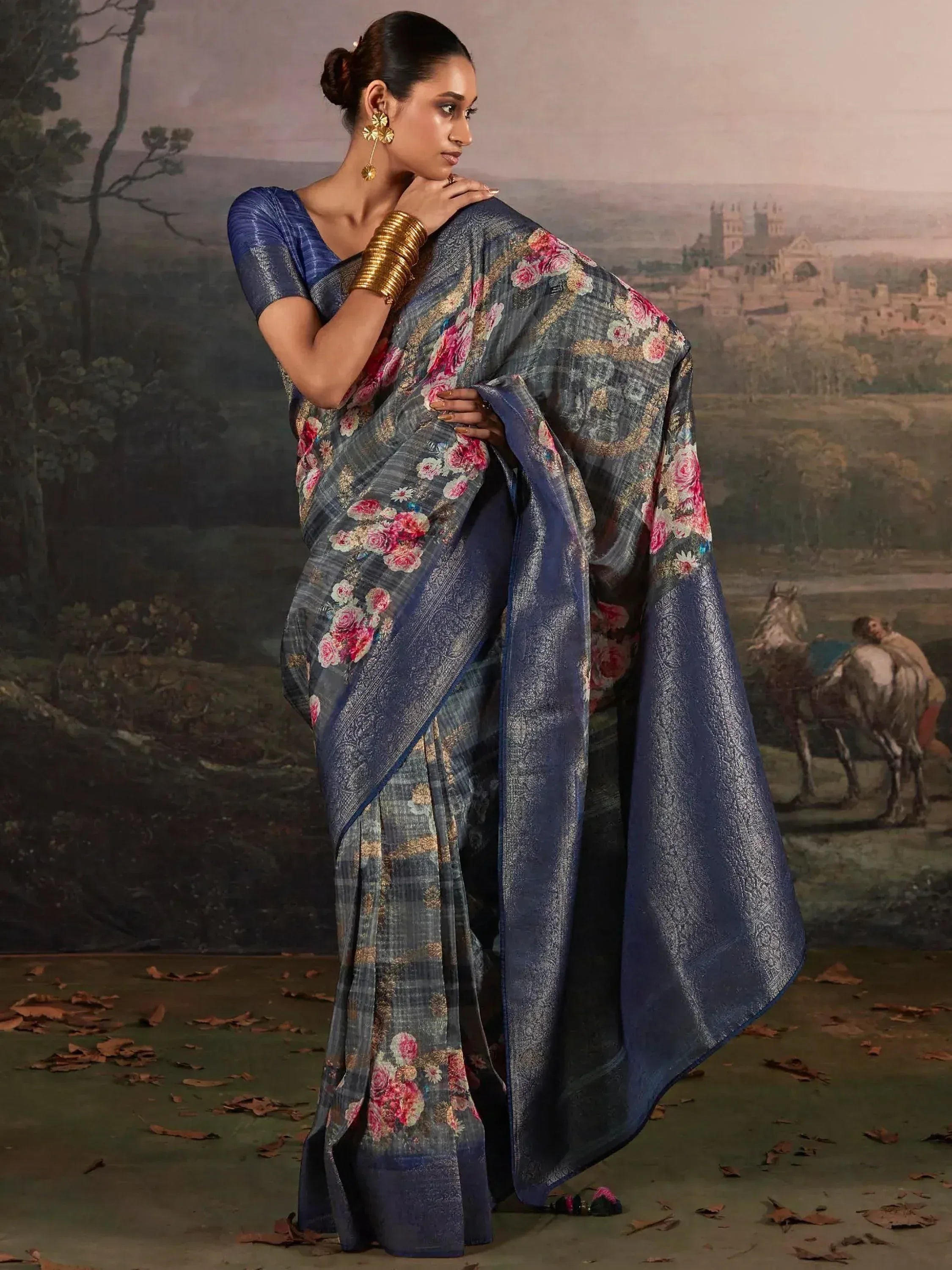 Woman in blue floral printed saree with gold embroidery, styled with matching blouse and traditional jewelry