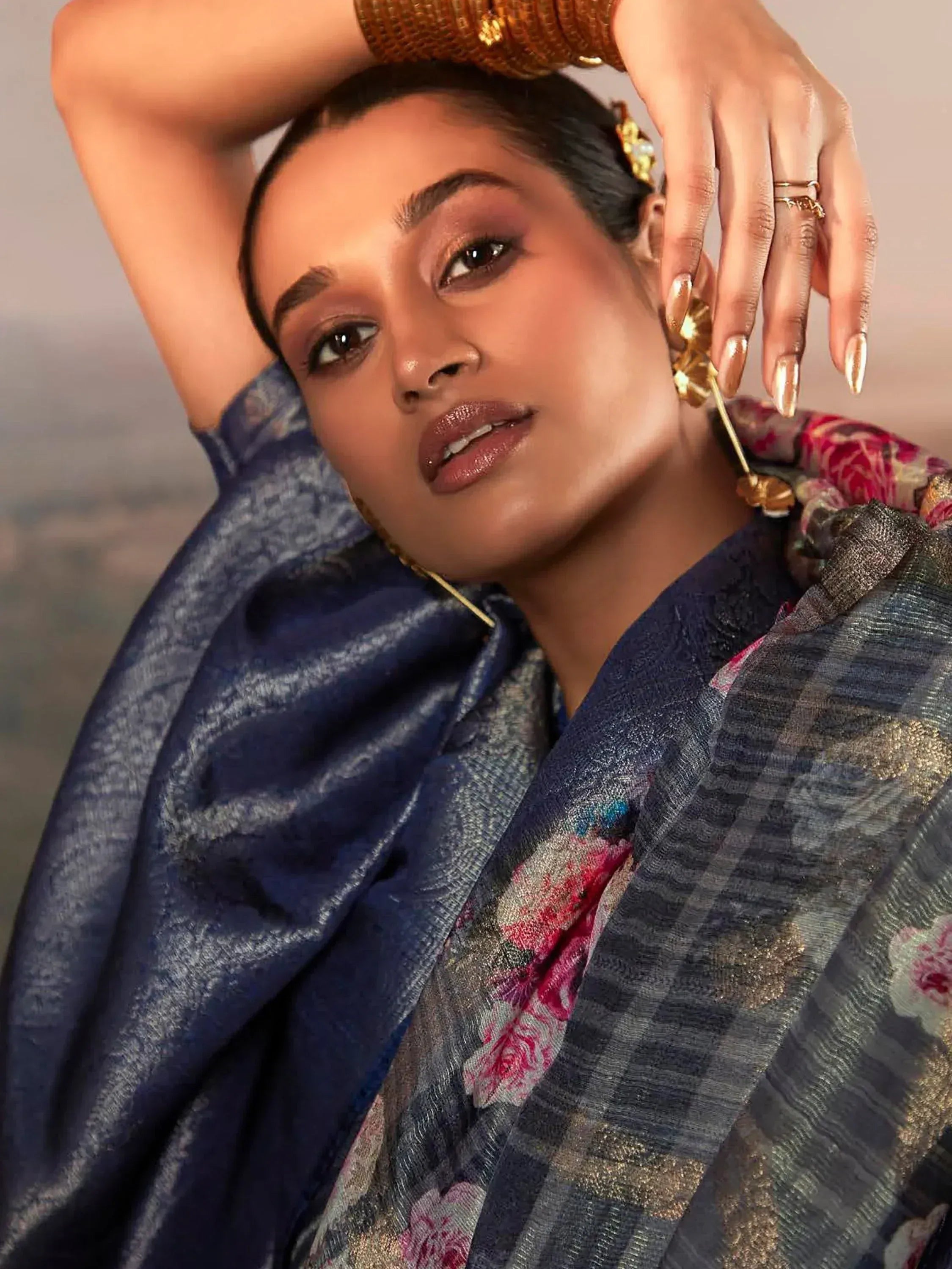 Woman in elegant blue floral saree with gold jewelry, showcasing Indian ethnic wear style