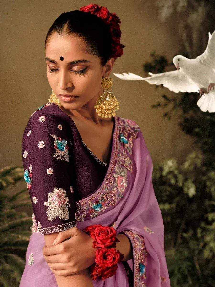 Elegant purple embroidered saree with floral details, gold jewelry, and red rose hair accessory