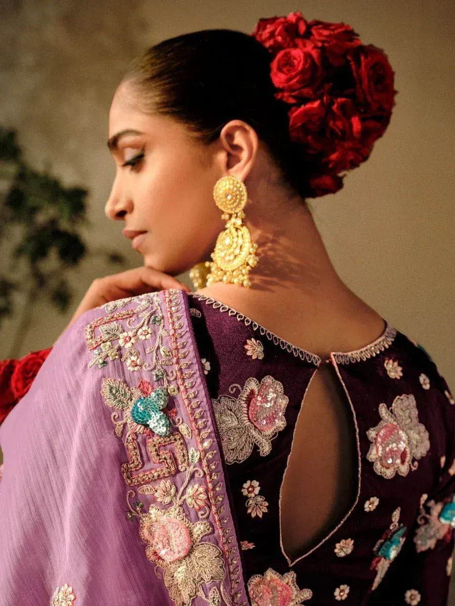 Elegant Indian ethnic wear with floral embroidery, gold jhumka earrings, and red rose hair accessory