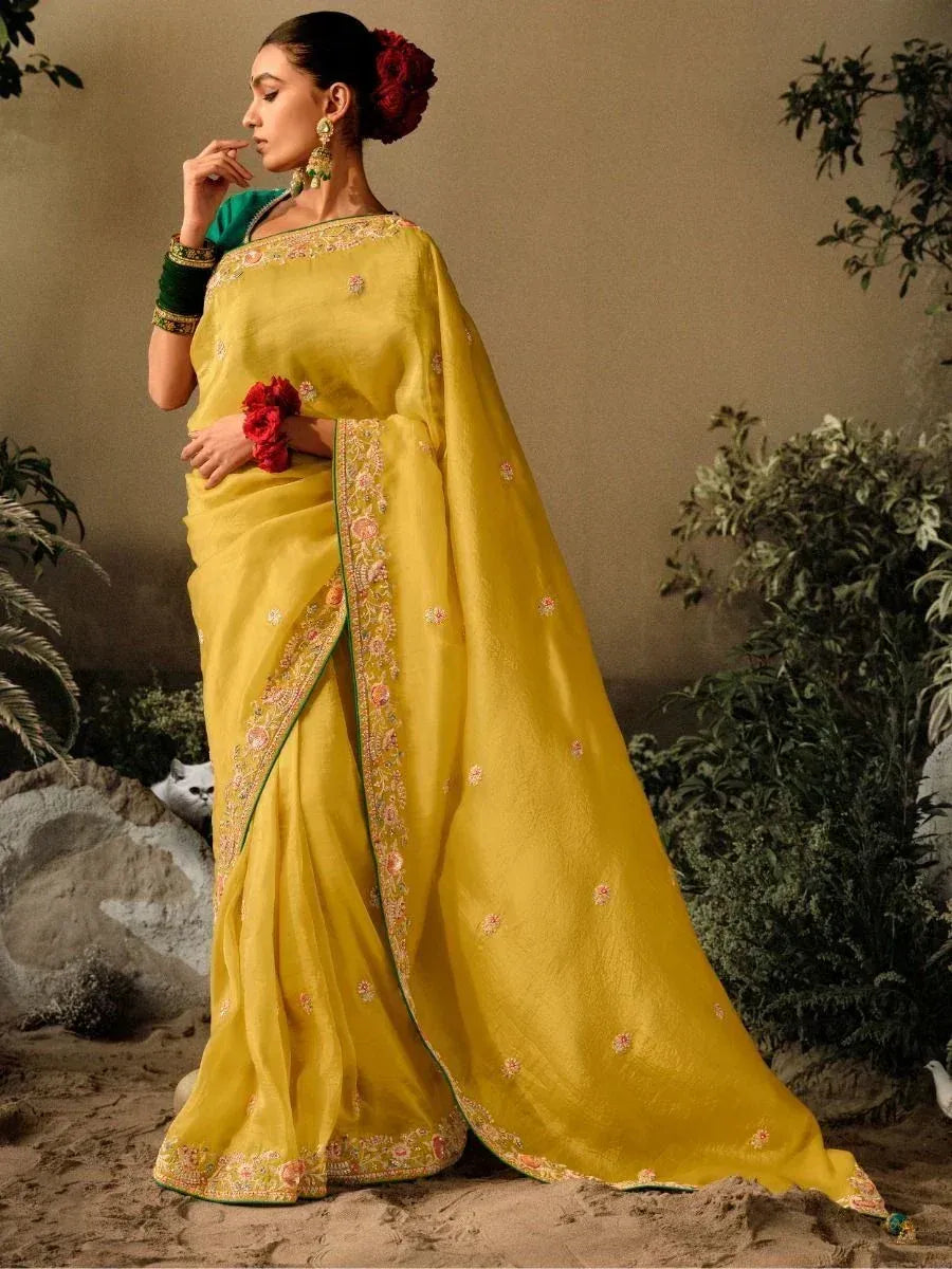 Elegant yellow saree with floral embroidery, green blouse, and red floral accents for Indian ethnic wear