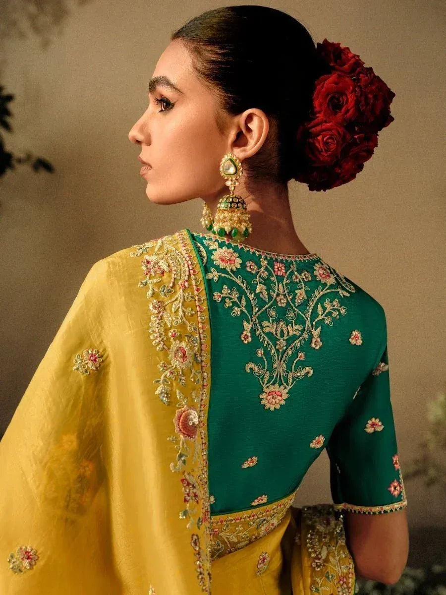 Elegant green and yellow embroidered saree with floral detailing and traditional jewelry