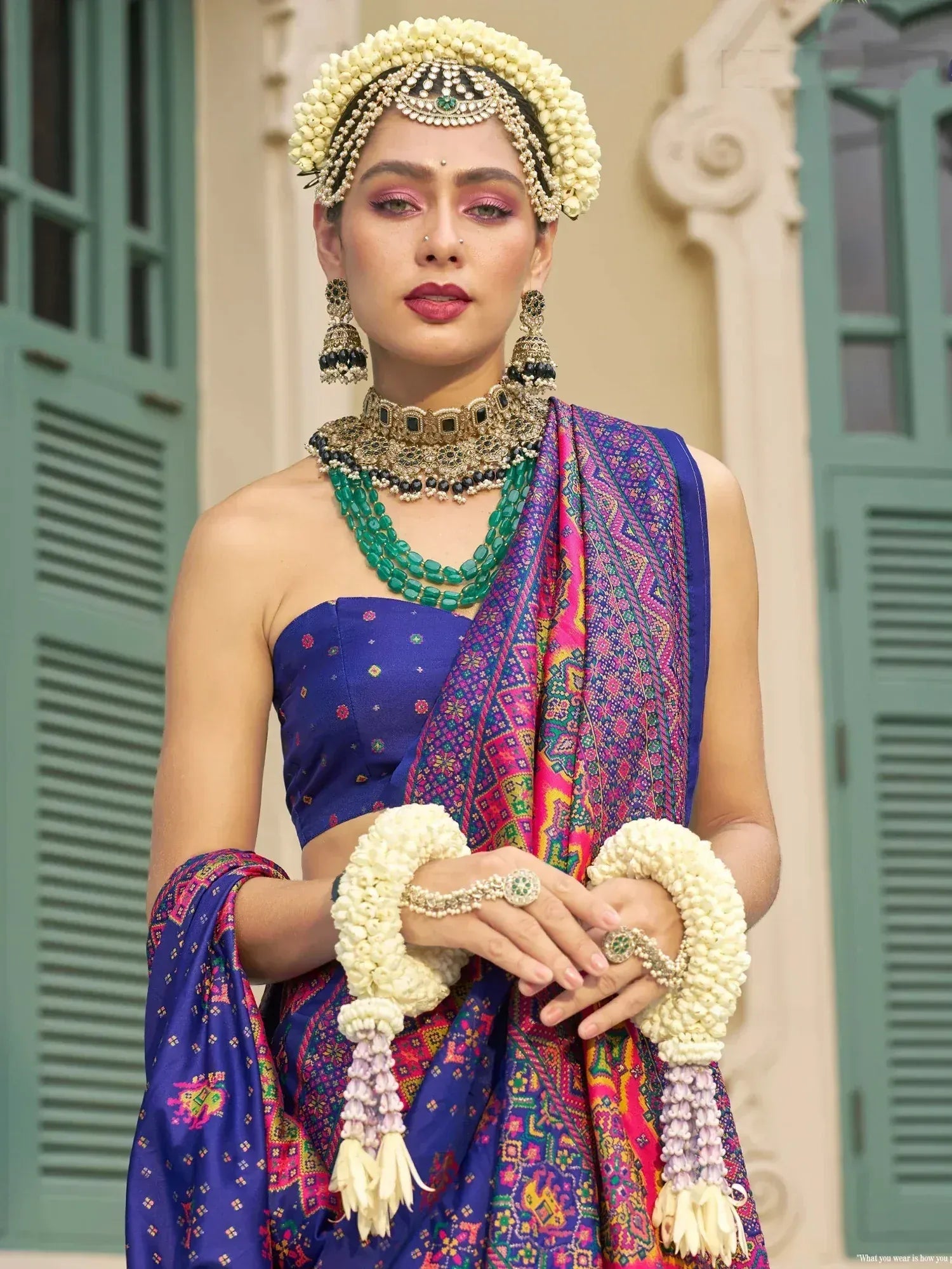 Woman in vibrant blue lehenga choli with floral jewelry, traditional Indian ethnic wear