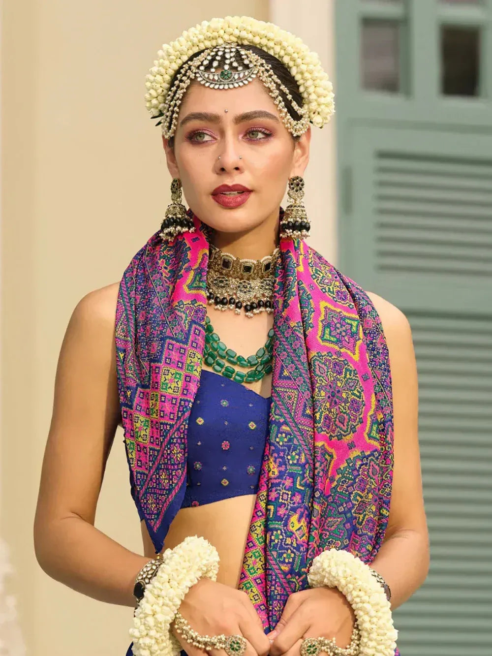 Woman in blue lehenga choli with floral jewelry and colorful dupatta, traditional Indian ethnic wear