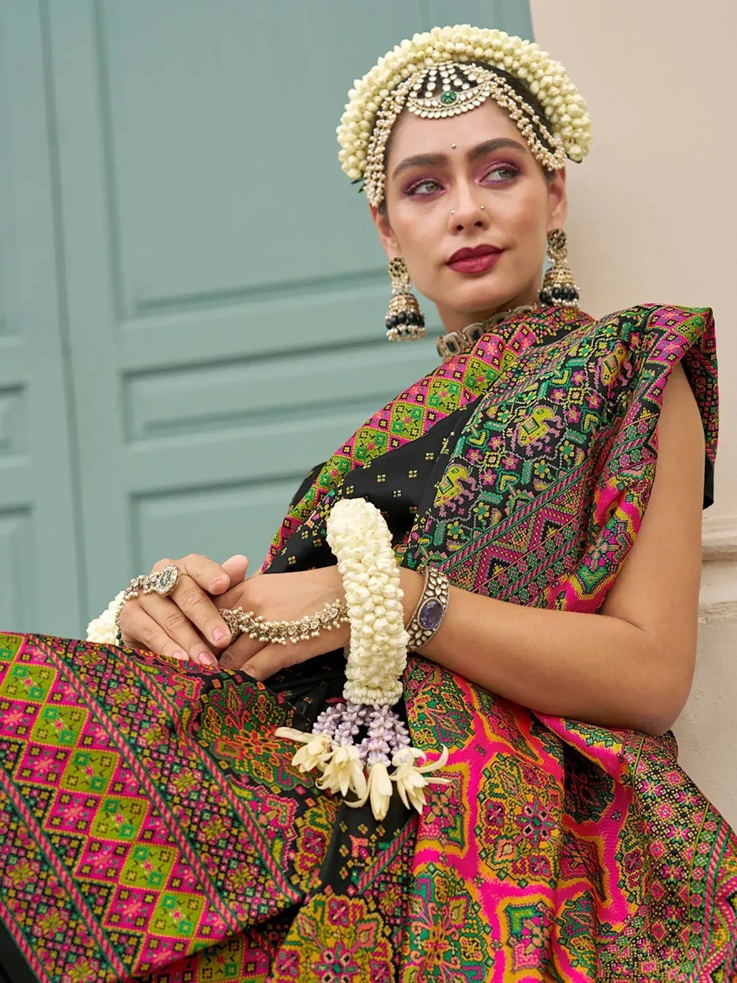 Woman in vibrant Indian ethnic saree with floral jewelry and traditional headpiece