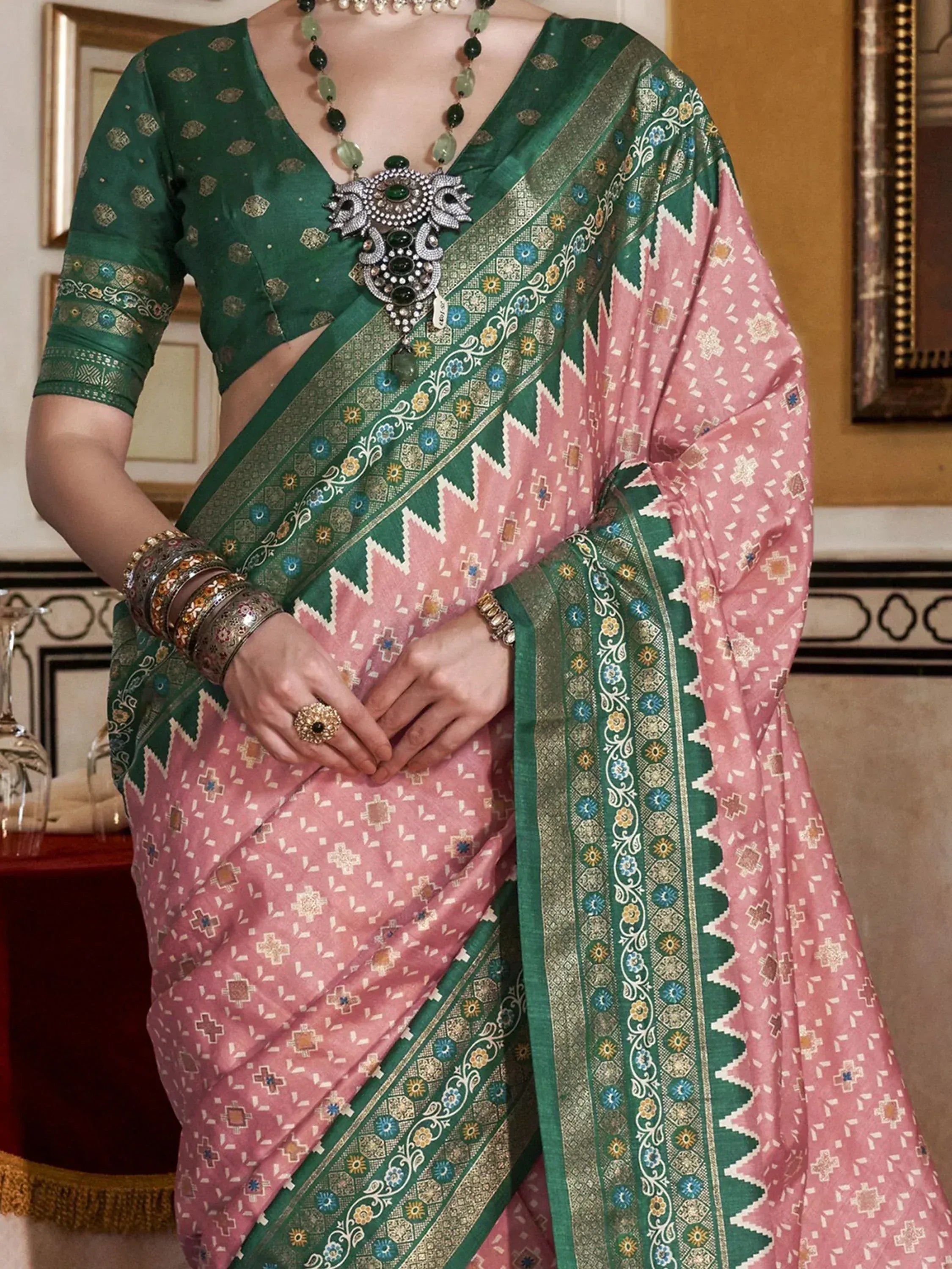 Pink and green printed saree with intricate border, paired with matching blouse and ethnic jewelry