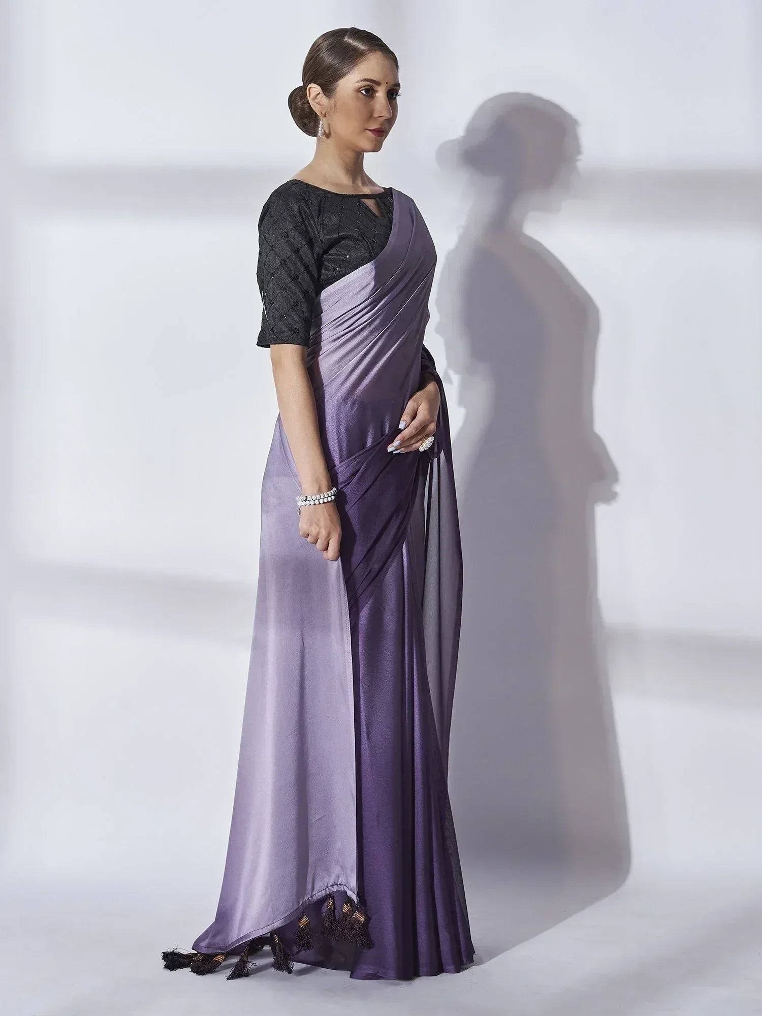 Elegant purple satin saree with black blouse, tassels, and sheer drape for Indian ethnic wear