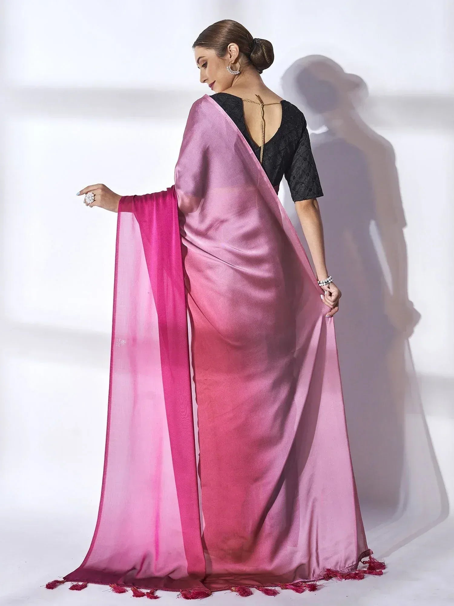 Woman in elegant pink ombre saree with black blouse, showcasing Indian ethnic wear style