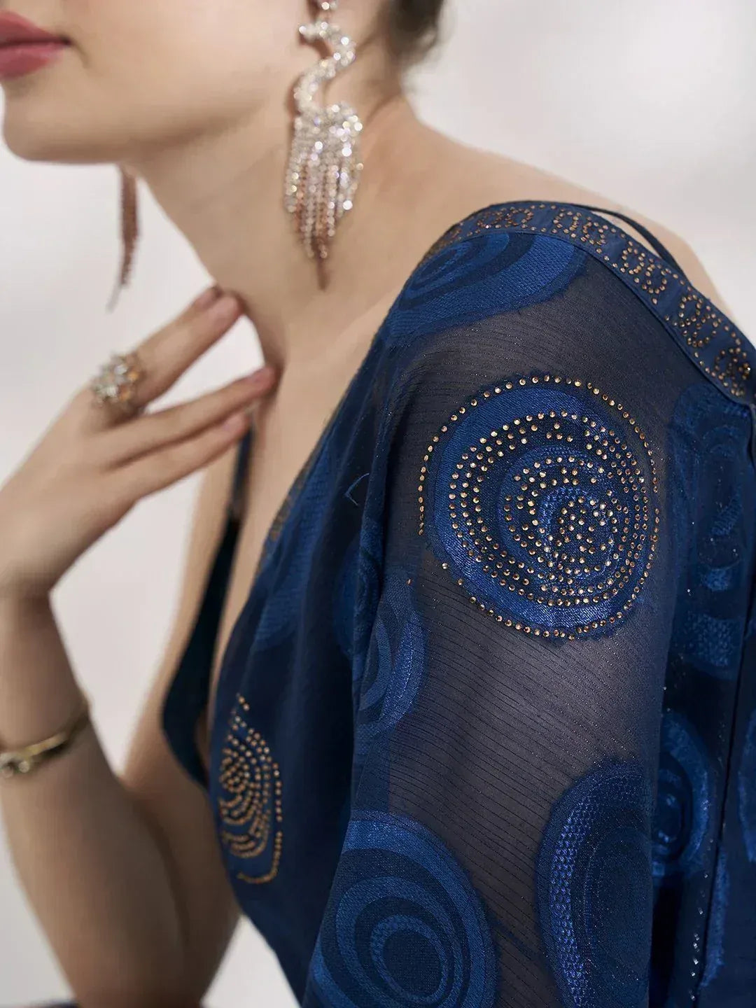 Blue ethnic gown with spiral embroidery and sheer sleeves, paired with statement earrings