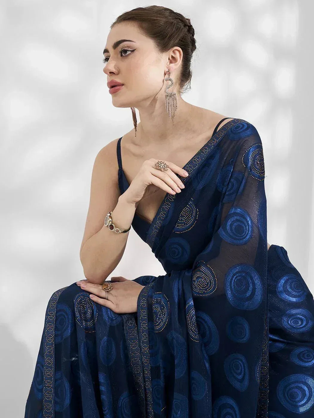 Elegant navy blue saree with spiral embroidery and sheer overlay, styled with statement jewelry for festive occasions