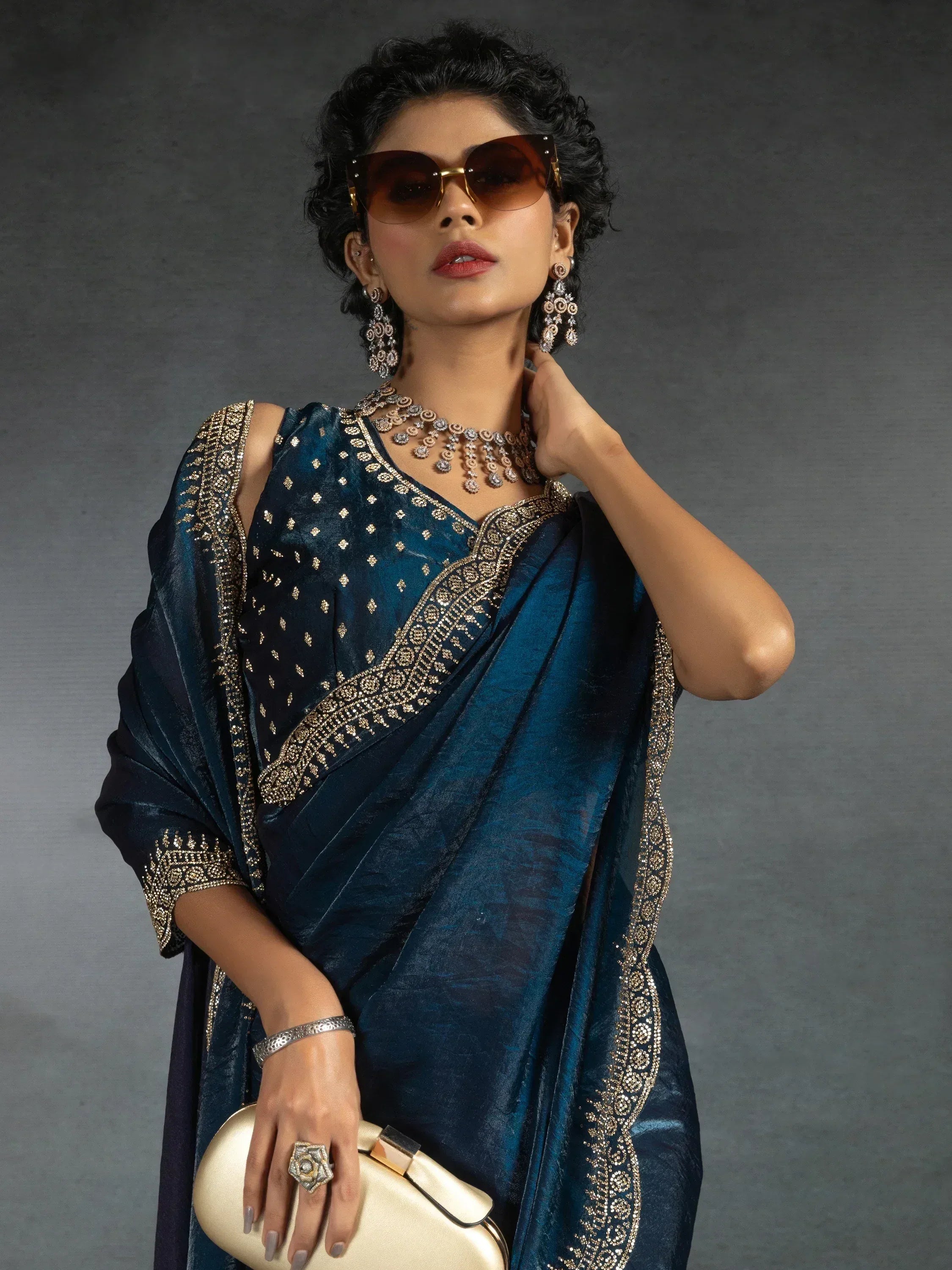 Elegant blue saree with gold embroidery, paired with statement jewelry and sunglasses